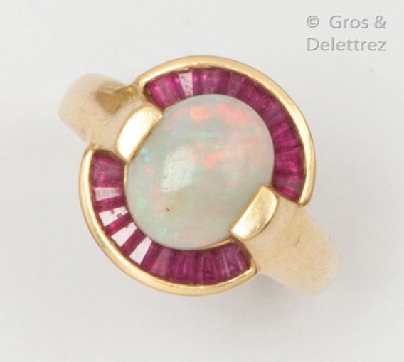 Null Yellow gold ring set with an oval opal in a frame of calibrated red stones.&hellip;