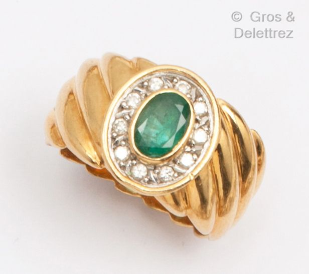 Null 黄金戒指，由一圈明亮式切割钻石中镶嵌的椭圆形祖母绿组成。手指尺寸：53/54。毛重：10.7克。