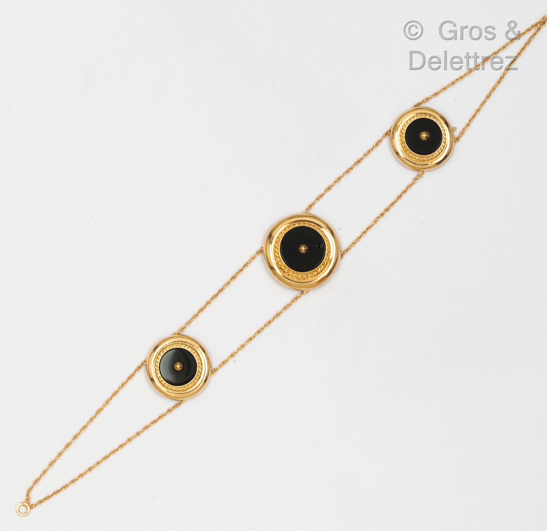Null 黄金手镯，由两条链子组成，链子上的圆形图案在扭曲的框架中镶嵌着黑玛瑙板，上面有一颗金珍珠。长度：18.5厘米。毛重：6.5克