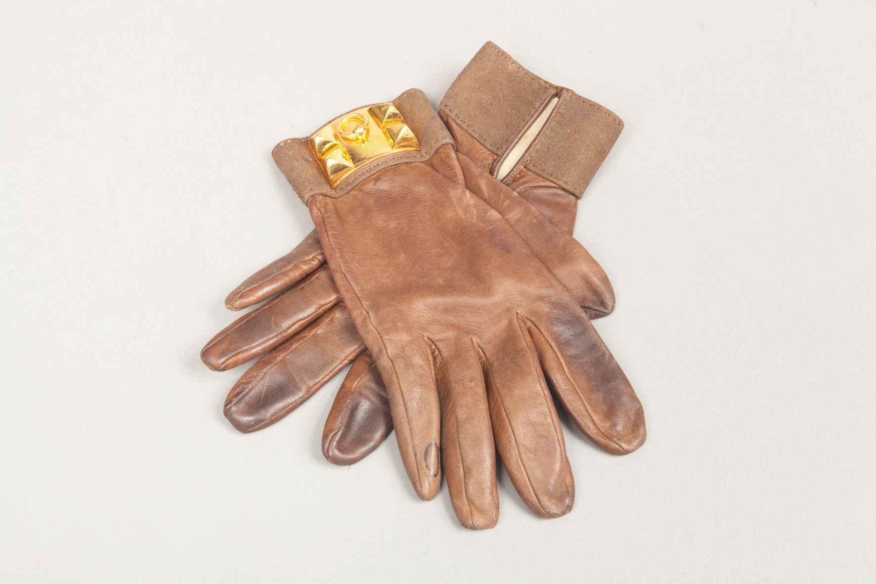 Null *HERMES Paris 法国制造 - 一对可可色小羊皮手套，天鹅绒小牛皮袖口，装饰有金色金属 "狗领 "图案。(磨损，污渍，衬里上有小的破损）。)