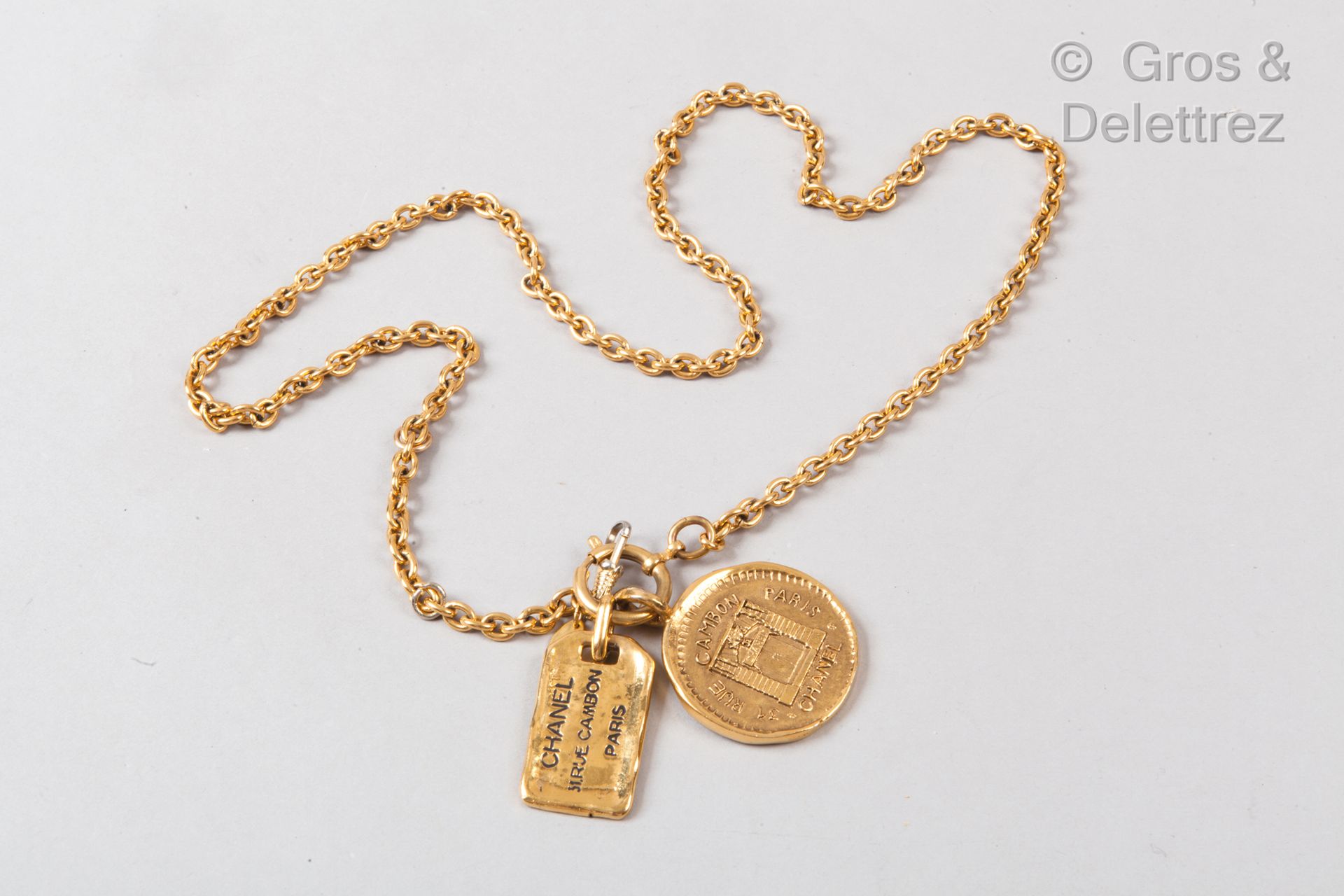 Null 卡尔-拉格斐的香奈儿

1988年春夏成衣系列

镀金的金属链子，上面有一个显示商店门面的徽章和一个黑色珐琅的长方形盘子，上面写着房子的名字。签名。长&hellip;