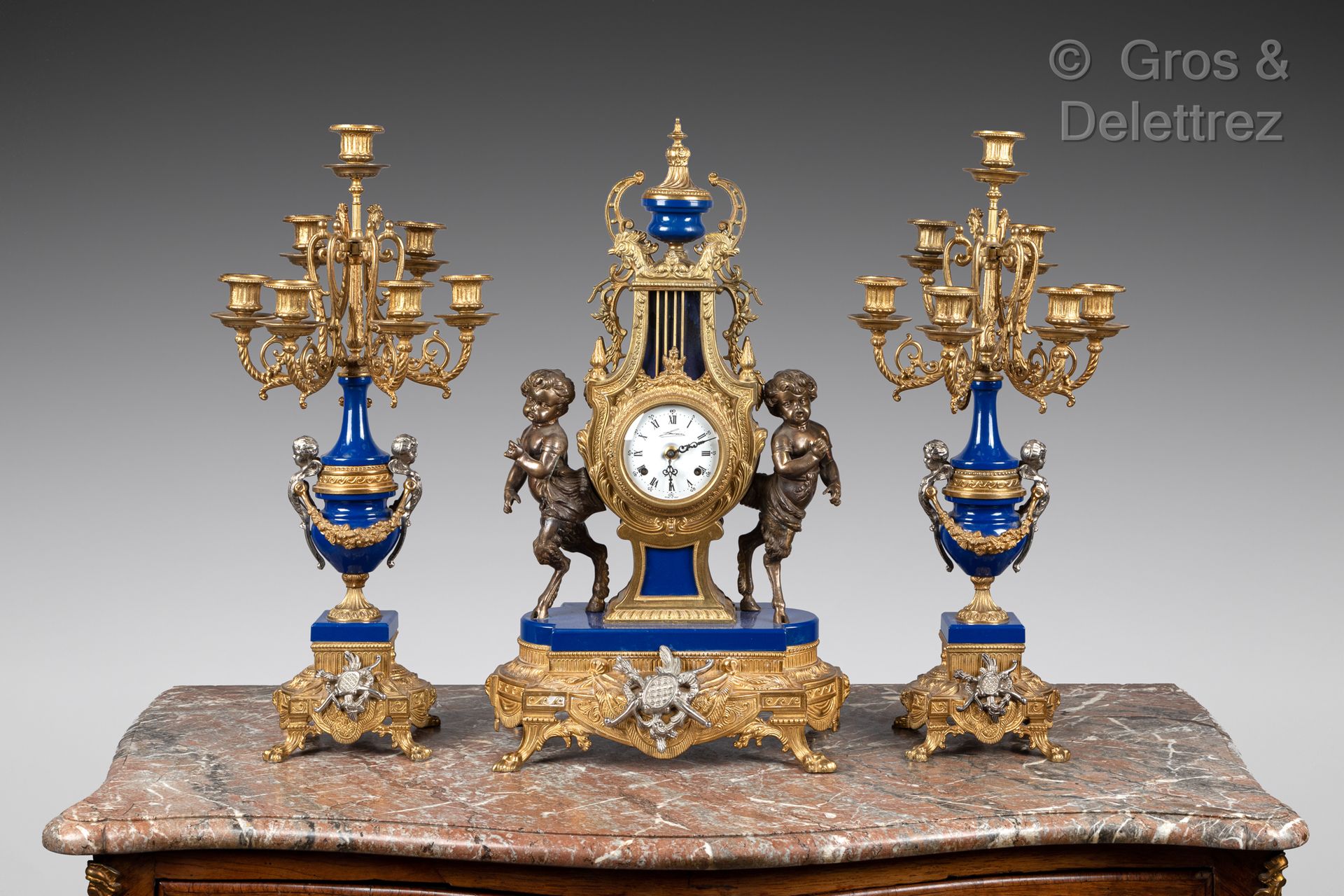Null 鎏金青铜，银色和部分蓝色珐琅的壁炉上有一个由两个年轻的小精灵和一对七臂烛台组成的琴键钟。

路易十六风格

高度：62厘米