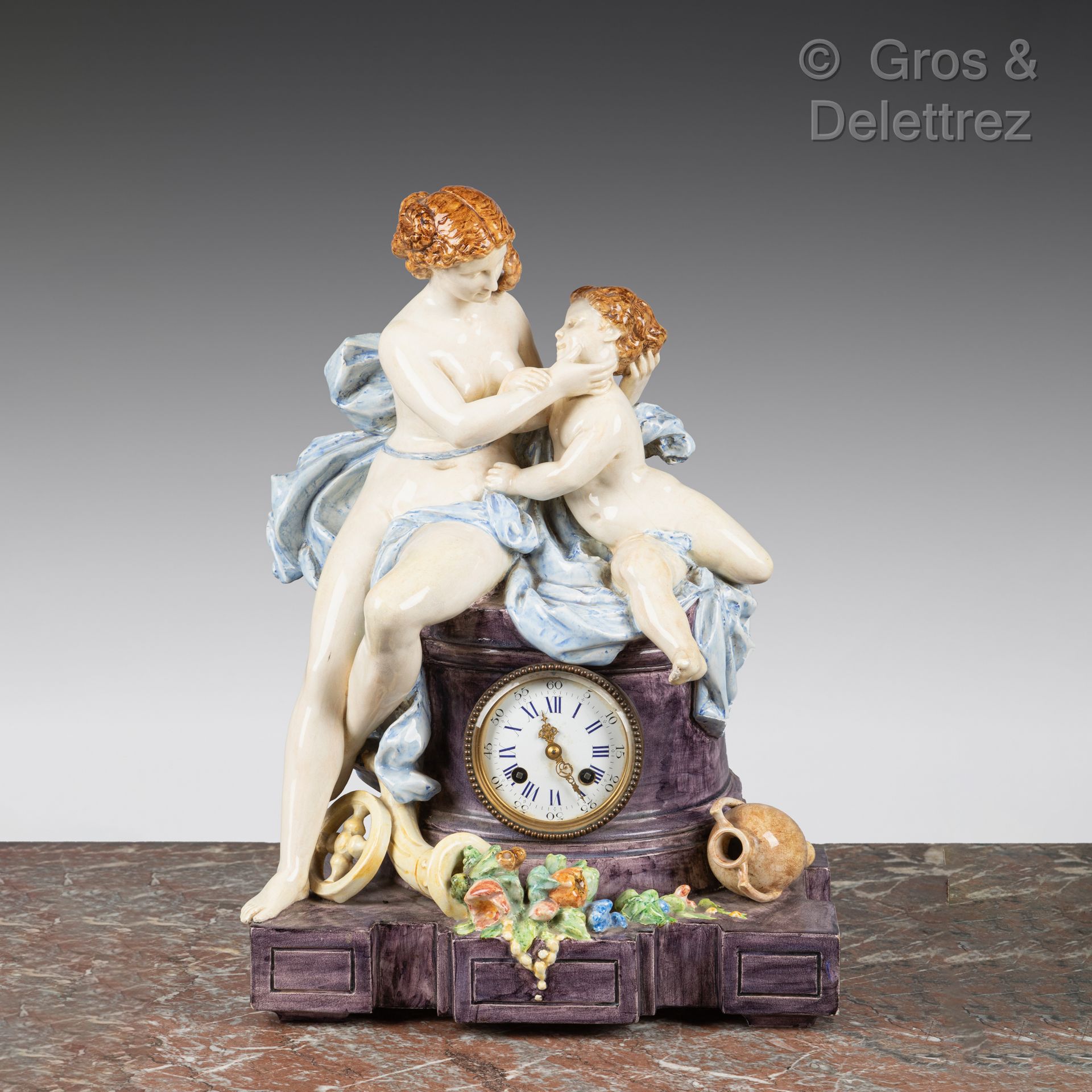 Null 多色珐琅彩陶瓷钟，显示维纳斯和爱情坐在半圆柱上，脚下是玉米棒。

背面署名 "Montigny-sur-Loing"。

高度：46厘米