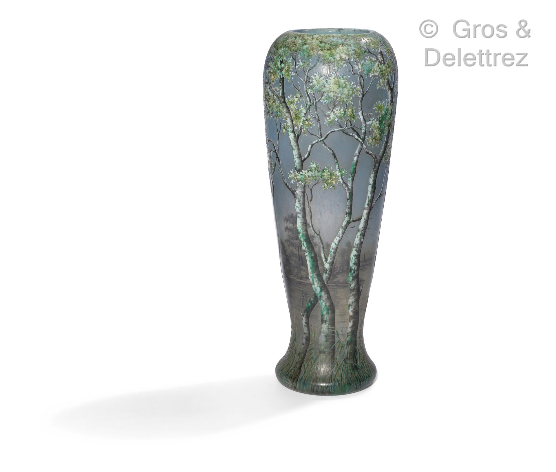DAUM Nancy 一个有衬里的玻璃柱形花瓶，酸蚀的装饰是在蓝色背景上用格子和绿色、白色和黑色色调的树木装饰的湖景。

签名为Daum Nancy。

大约1&hellip;