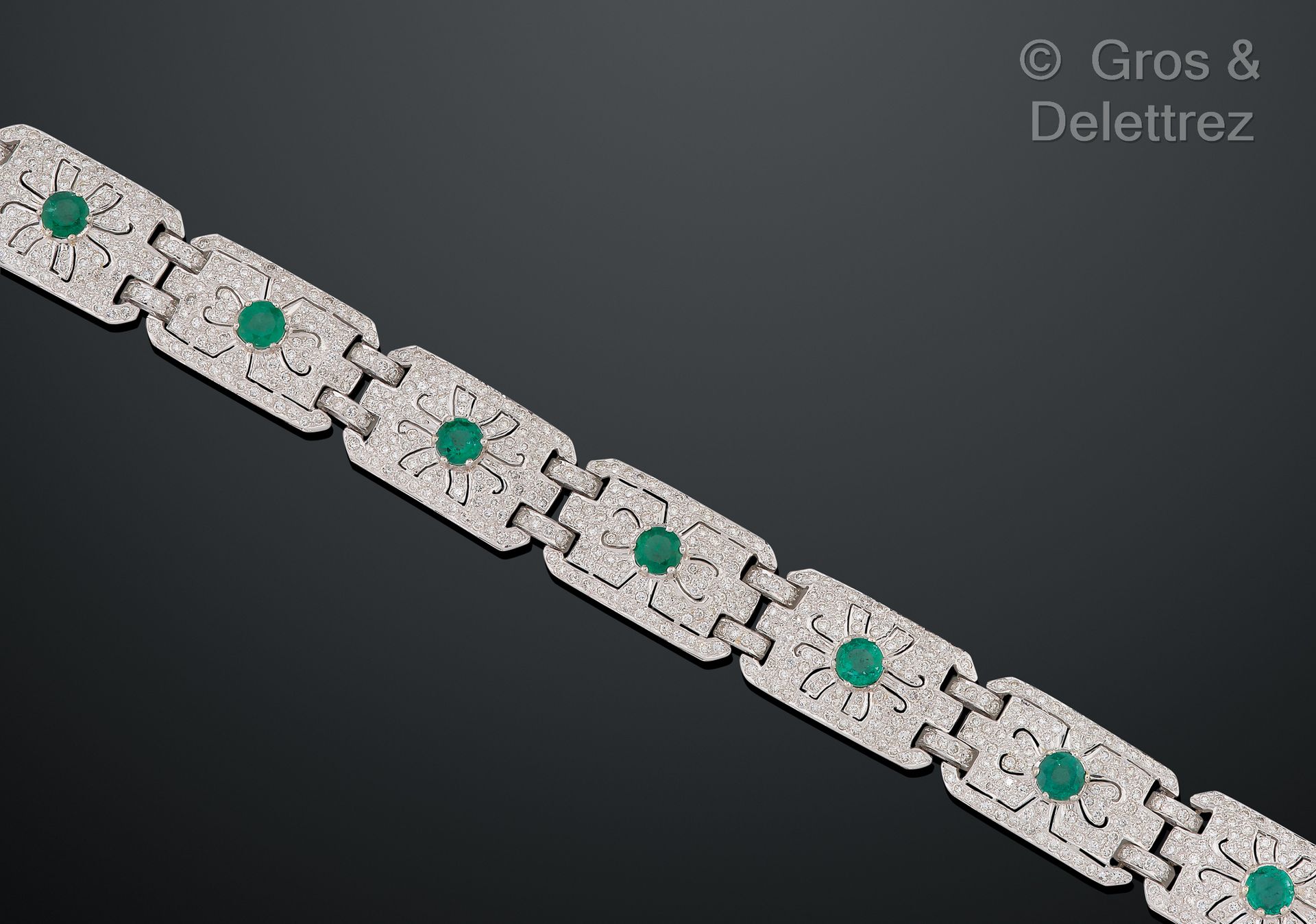 Null 白金铰链式手镯，由完全镶嵌明亮式切割钻石的几何图案的链节组成，顶部有圆形刻面的祖母绿。长度：19厘米。毛重：37.5克。