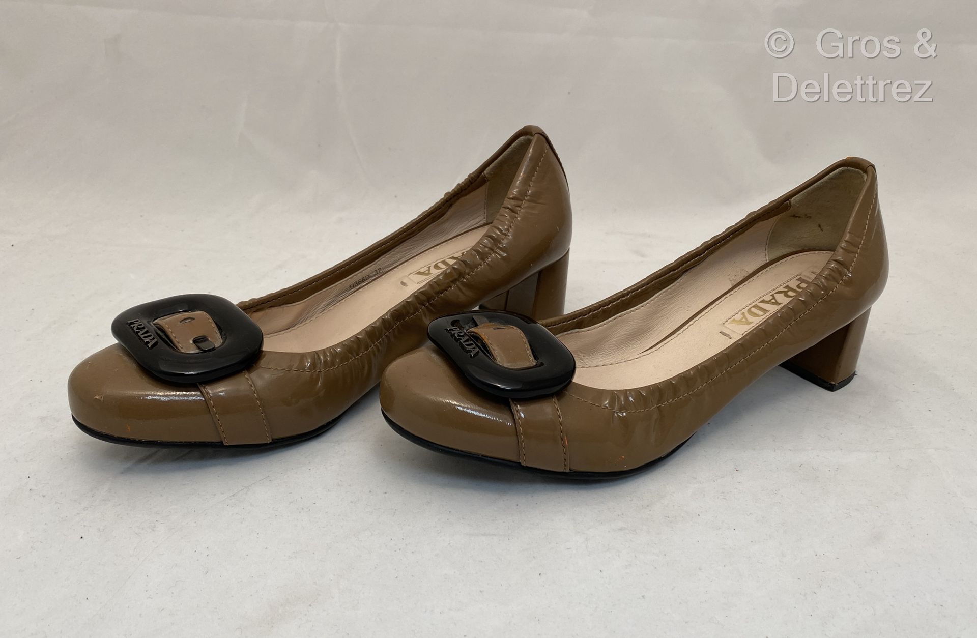 Null PRADA 灰褐色漆皮高跟鞋一对，鞋面装饰有大型黑色复合扣，4.5厘米有盖高跟鞋。T 37.BE (污渍)