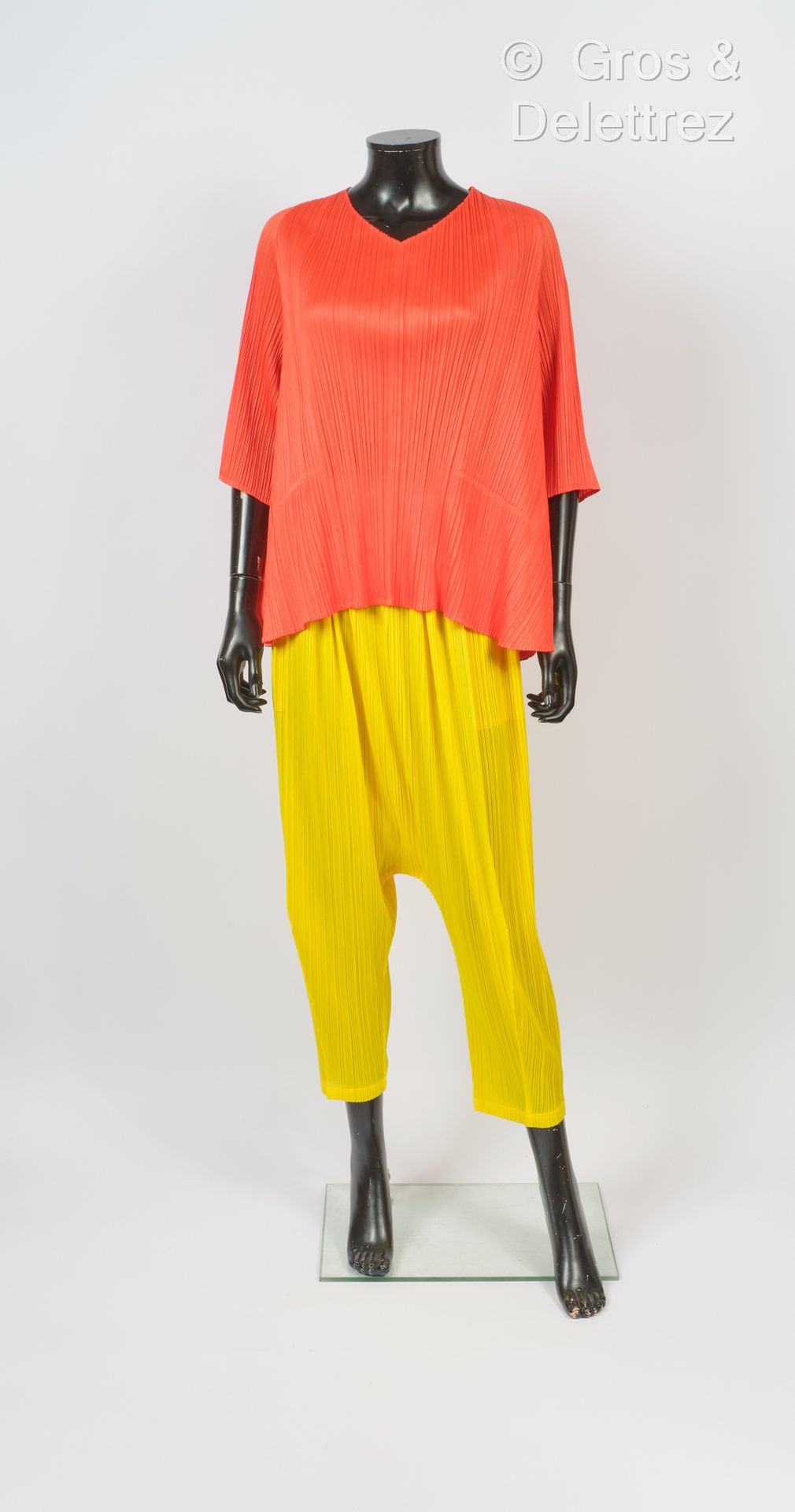 PLEATS PLEASE 褶皱的聚酯服装，包括一件橙色的喇叭形上衣，V领，小袖子，和黄色的沙罗尔式长裤。白色的爪子，灰色的图形。T. 5.