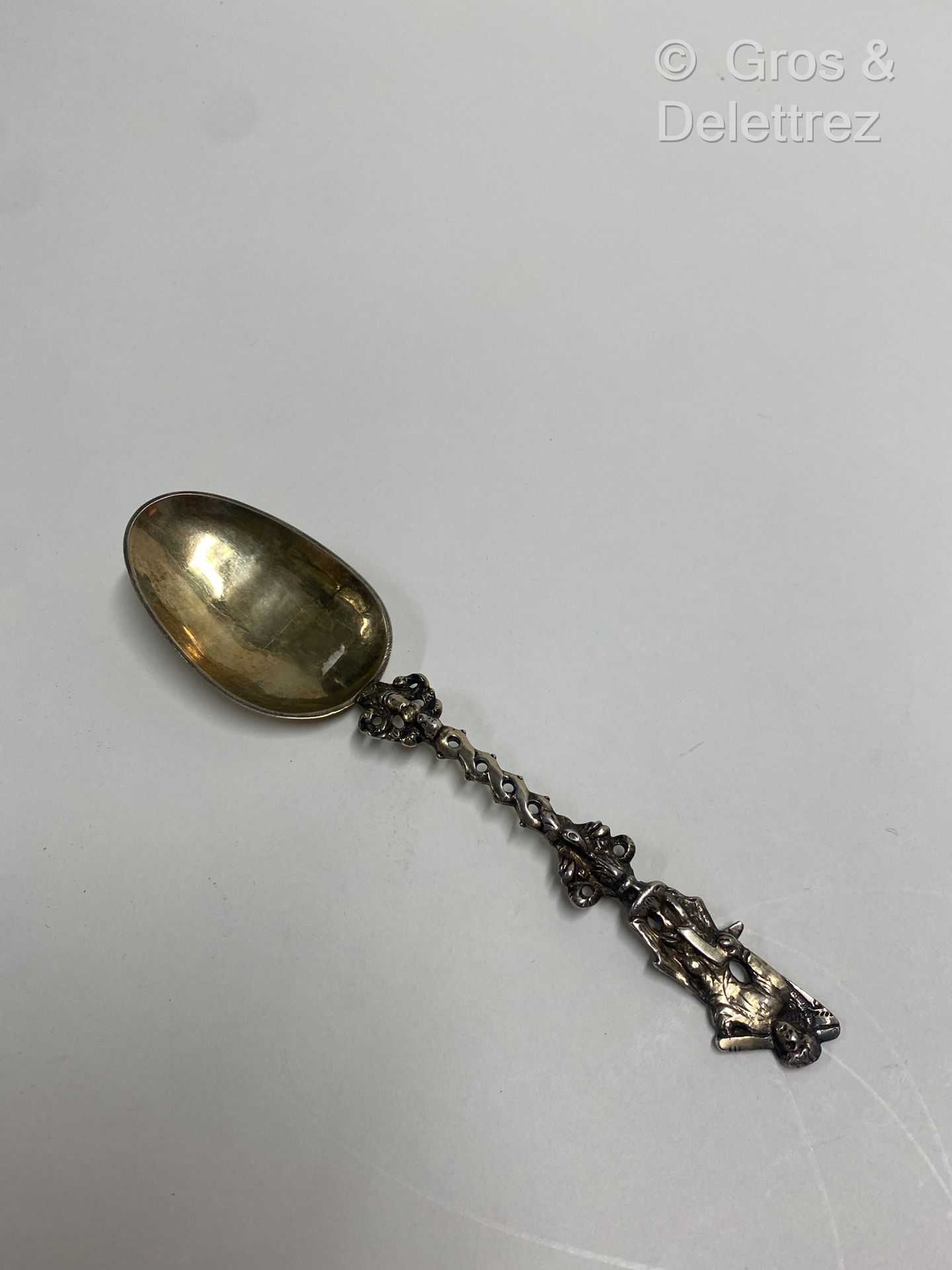 Null (E) 一把银制和镀金的婚礼勺子，扭曲的手柄上有一个小天使的半身像，上面有一个手持方形的人物。

荷兰，19世纪

重量：40克 - 长度：19厘米