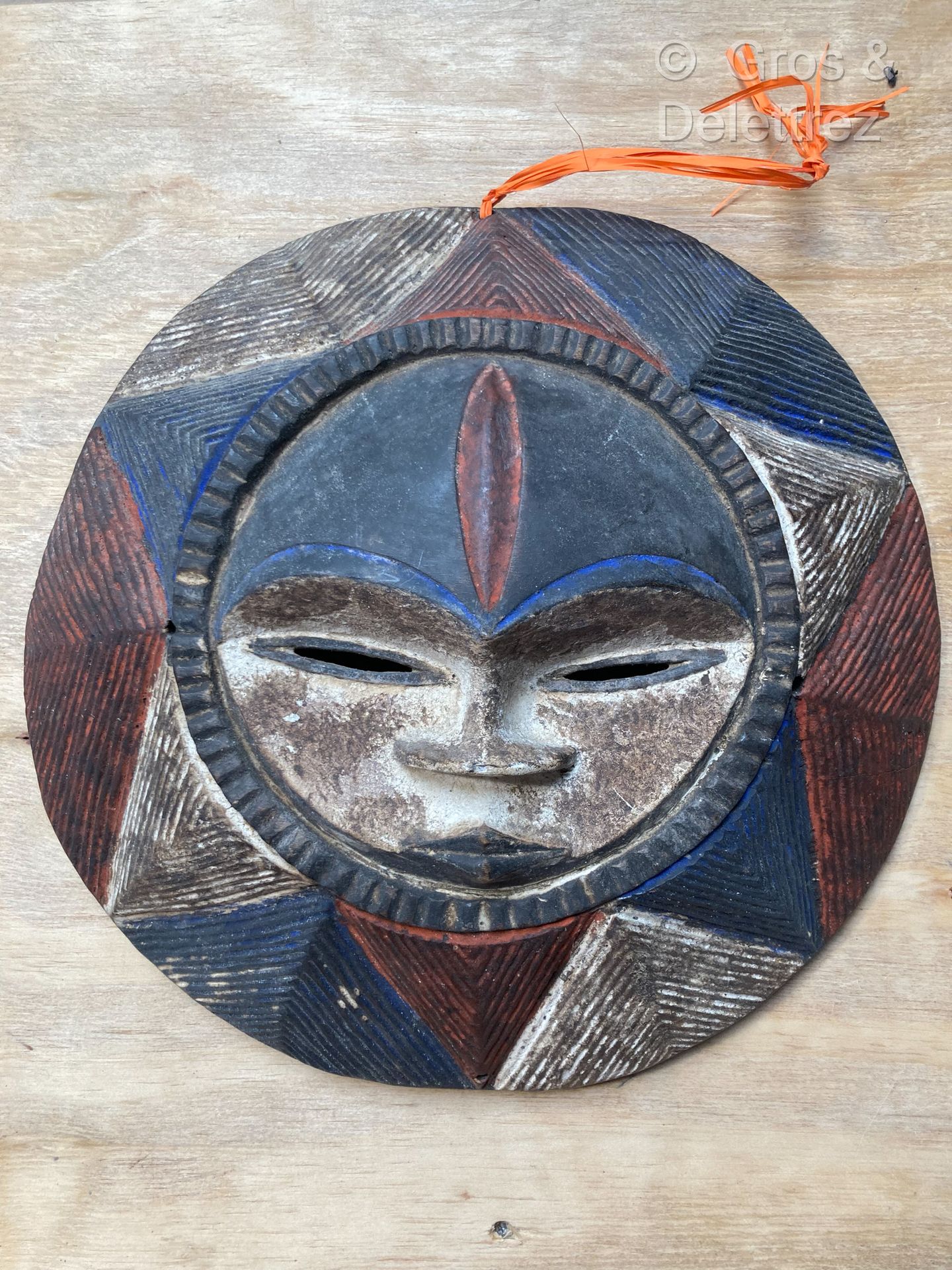 Null 圆形面具，以铜化和多色的木头制成，有三角形的装饰。
直径：34厘米。