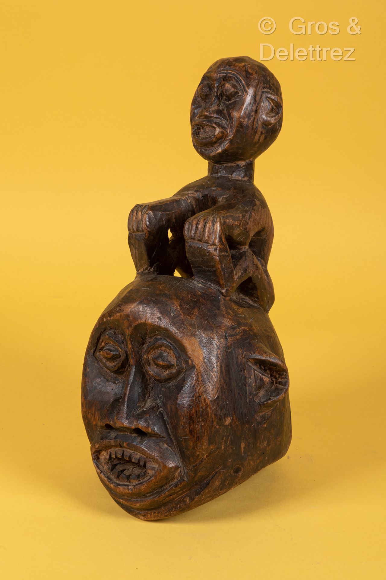 Style Bamiléké / Bangwa CAMEROUN 染色的木制面具，显示一张狰狞的脸，上面有一个坐着的人物。
高度：40厘米。