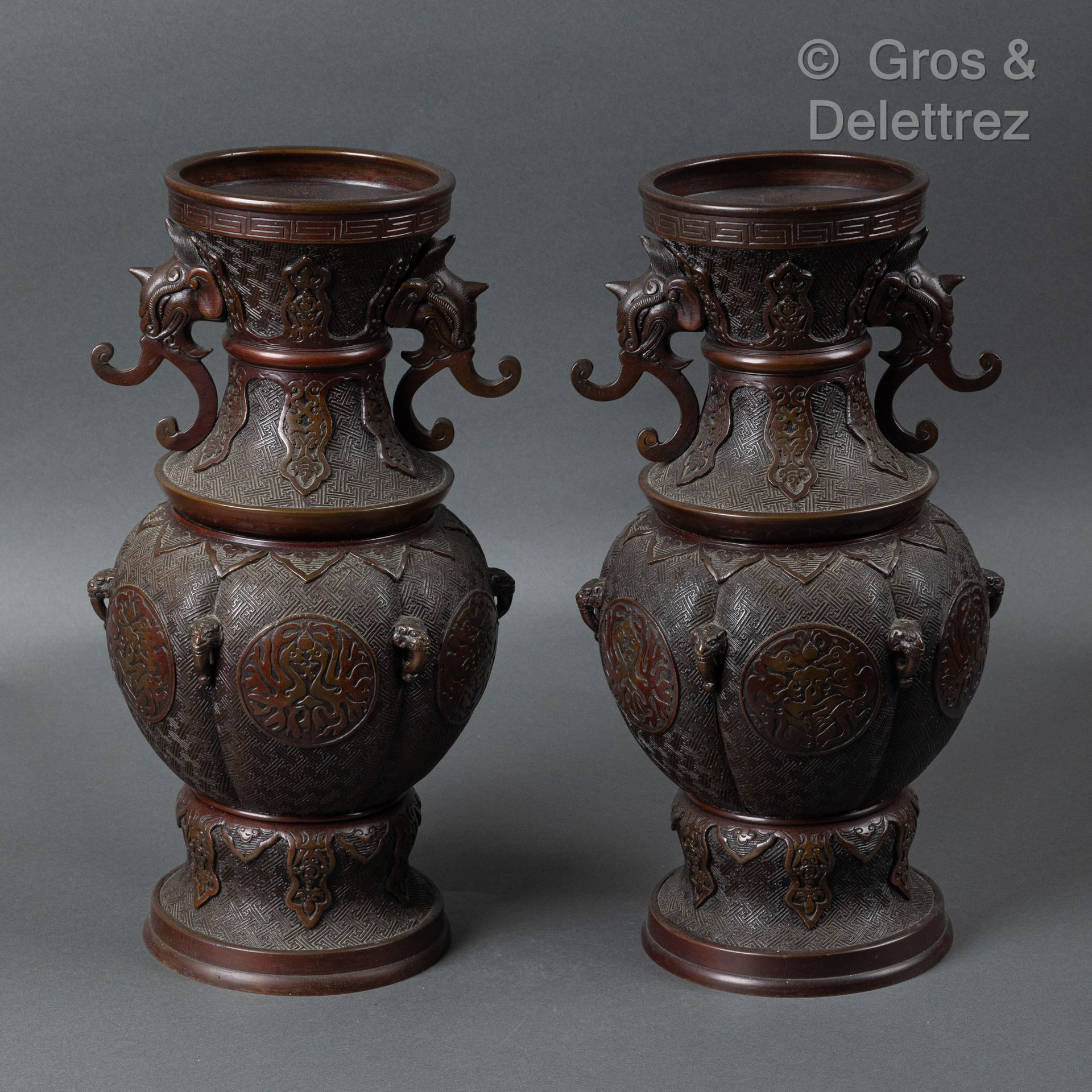 Null 日本，明治时期
一对青铜柱形花瓶，几何背景上有凤凰对峙的徽章装饰，颈部装饰有两个象头造型的把手。 
H.41.5厘米
