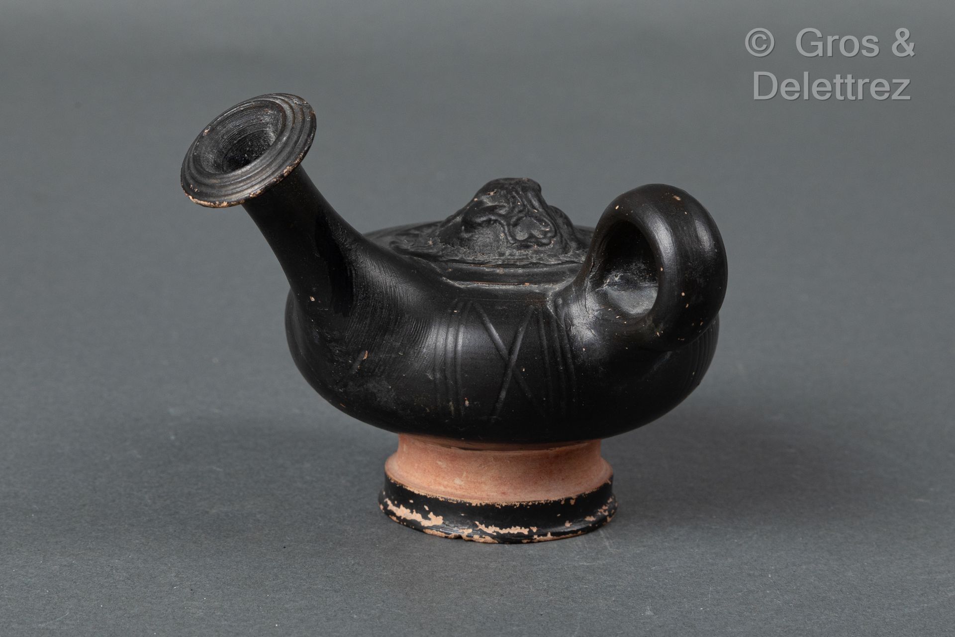Null 黑色珐琅彩陶罐，手柄上有狮子马夫的装饰。 
马格纳格拉西亚，4世纪。 
H.9厘米 长13厘米