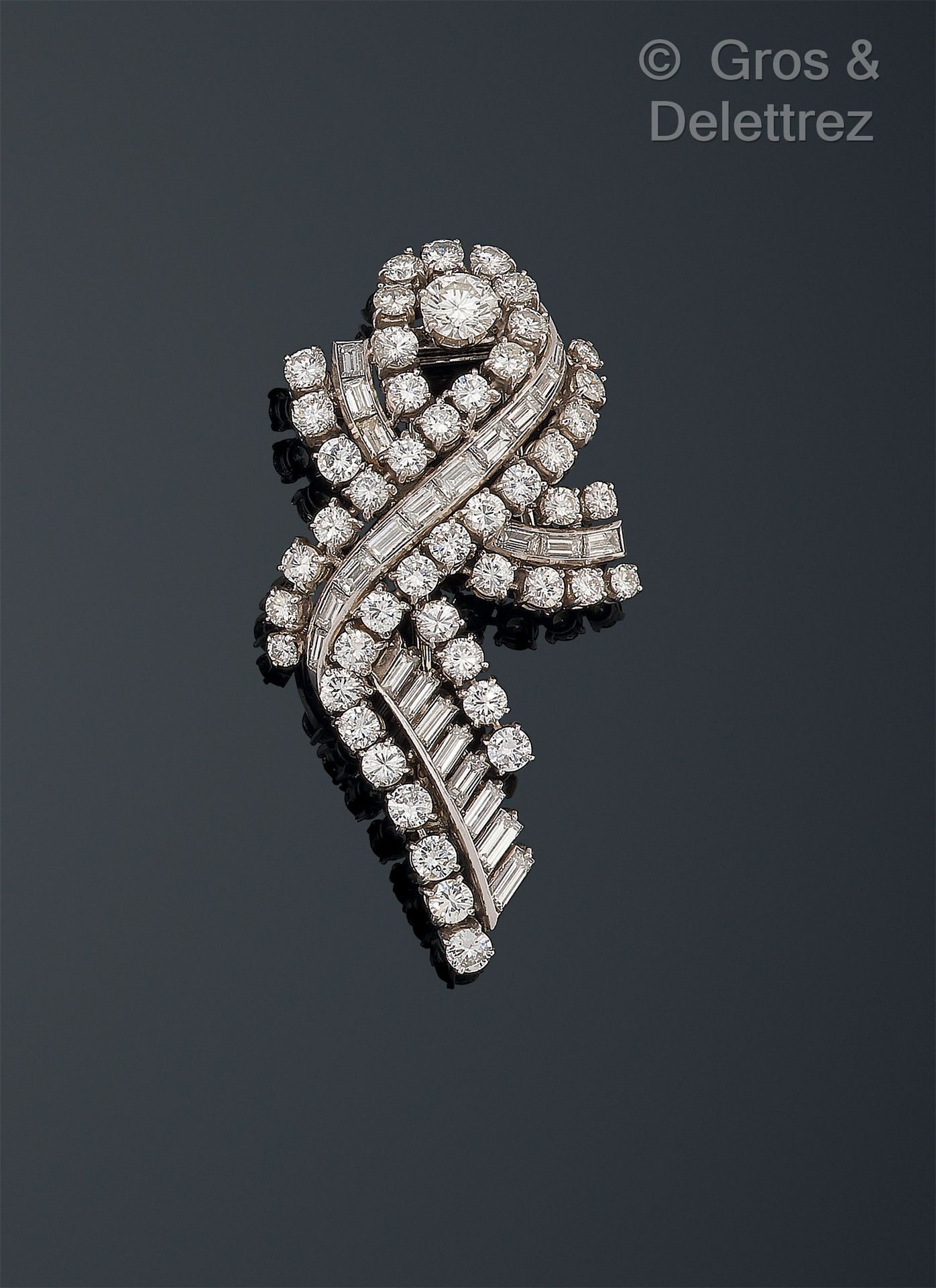 Null 法国作品，1950-1960 - 750千分之一白金和950千分之一铂金的涡旋式领夹，镶嵌明亮式切割和长方形切割钻石。徽章为千分之七十五的白金材质。
&hellip;