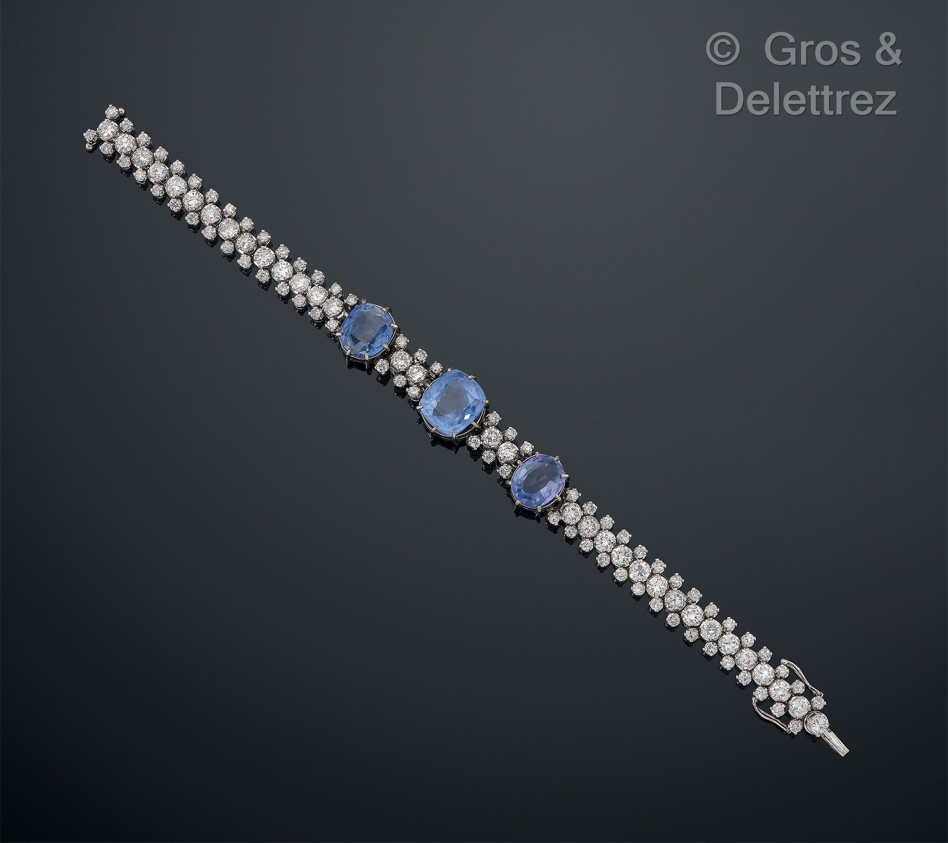 Null 铰链式手镯，由75万分之一的白金镶嵌三颗枕形切割蓝宝石，放在一排明亮式切割钻石上，边上是两排较小的明亮式切割钻石。蓝宝石的尺寸：11.5x10.2x6&hellip;