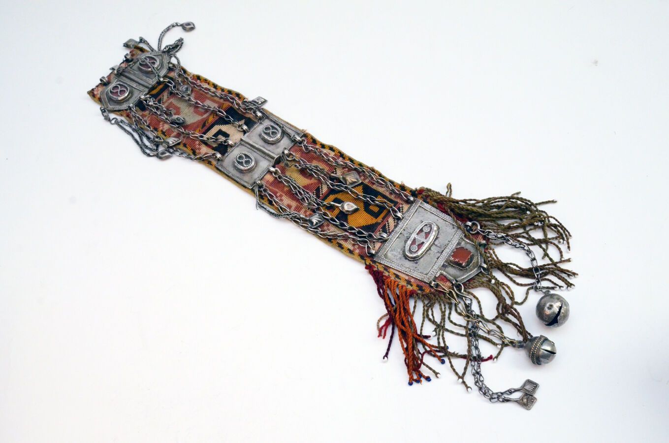 Null 带状元件
缝制在织物上，3个银制元素，颗粒状，凹凸状和玻璃状，带有吊坠和链条。
哈萨克斯坦，20世纪。
长度：37.5厘米。 
H.5.5厘米、6.5&hellip;