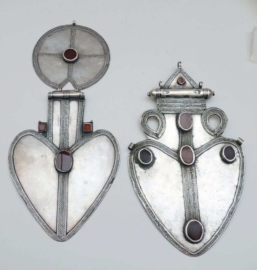 Null 两个银质阿兹克背饰
银质，心形，一个有一个图玛，另一个有一个双圆吊坠，丝质，颗粒状，镶嵌有凸圆形红玉髓。 
土库曼斯坦，埃尔萨里，20世纪。
尺寸：3&hellip;