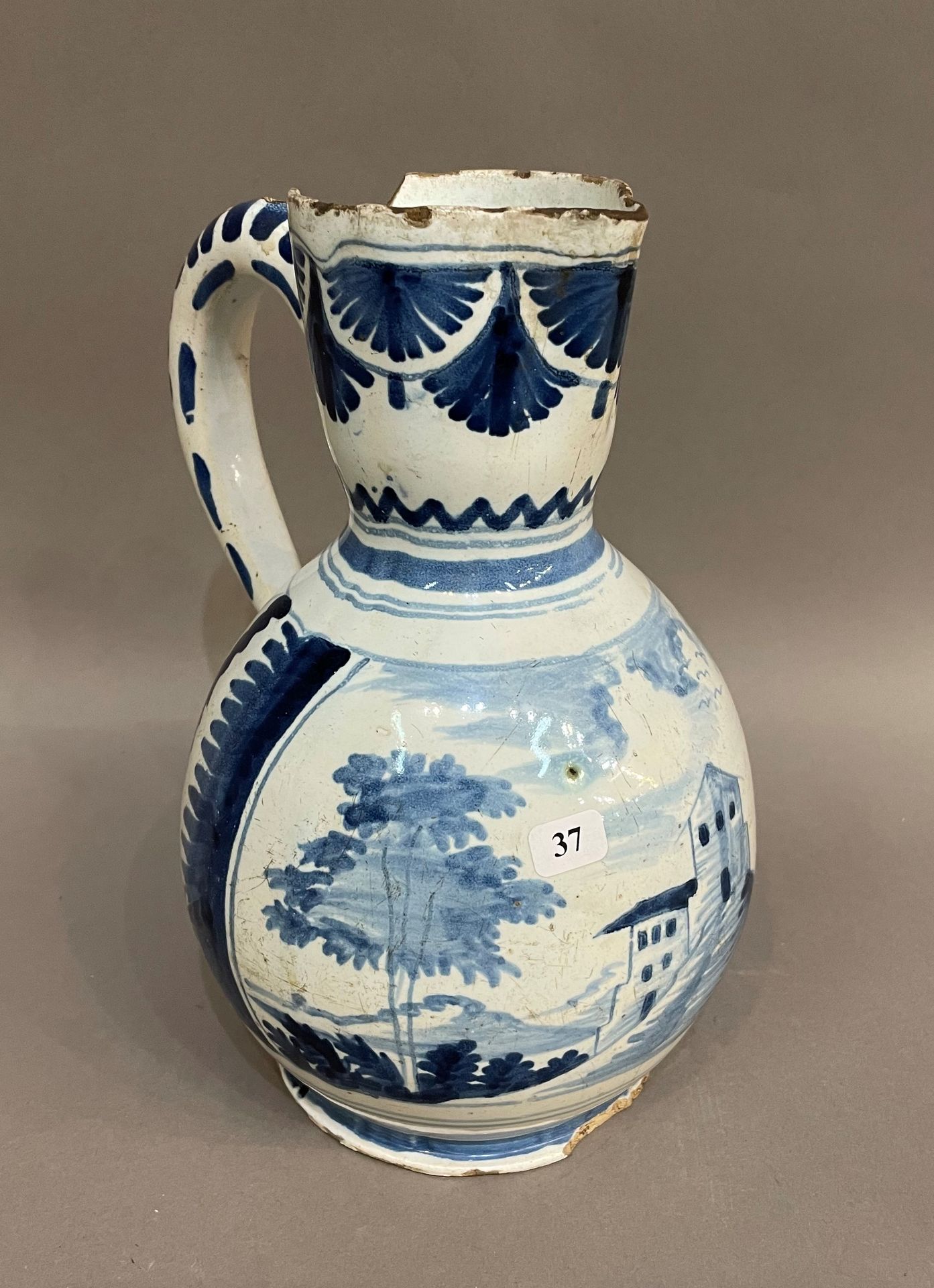 Null 鲁昂

一个陶罐，颈部有蓝色的单色装饰，上面有房屋和树叶的风景。

18世纪。高24,5厘米。

缺口和缺件。