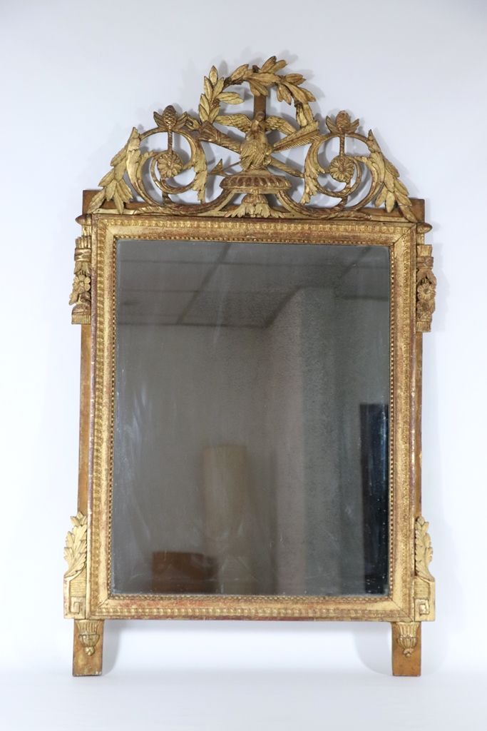 Null 长方形的镜子，装饰有珍珠楣，装在一个18世纪的雕刻和镀金的木框里，有一个镂空的踏板，装饰有一对在箭筒上的鸟，在月桂叶的皇冠下。尺寸：130x77厘米