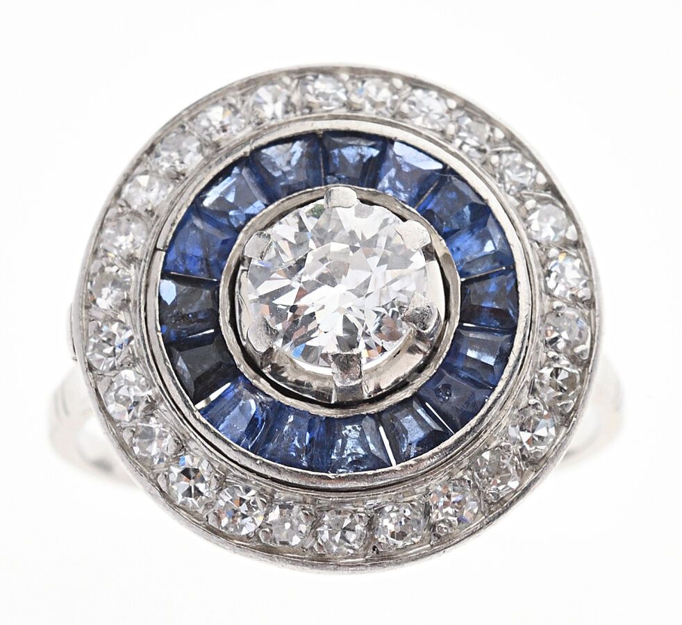 Null 一枚铂金戒指，在校准的蓝宝石和较小的钻石的双重镶嵌下，镶嵌了一颗0.60克拉的半切割钻石。法国作品，装饰艺术时期，约1920年。手指大小：52。毛重：&hellip;