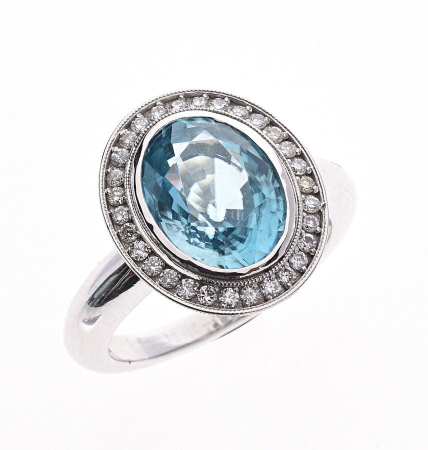 Null 蓬巴杜 "750/°°白金戒指，在一圈明亮式切割钻石中镶嵌了一颗约6克拉的大椭圆形蓝色锆石。手指大小：57。毛重：8.5克。