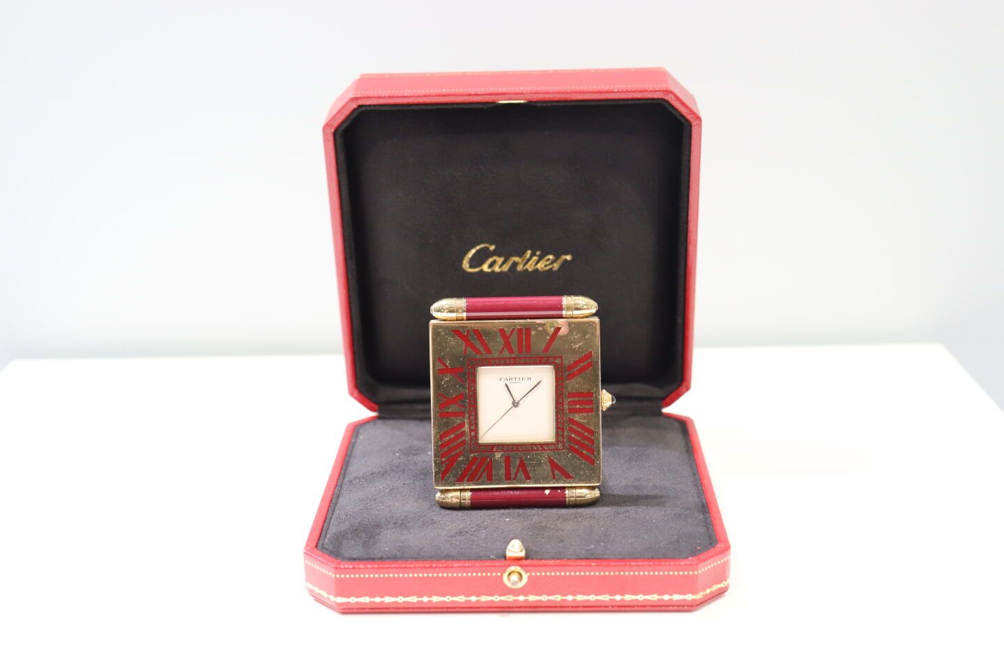 Null CARTIER - 鎏金和酒红色金属长方形时钟，白色表盘，银色指针，石英机芯。有编号。有一个箱子。事故。