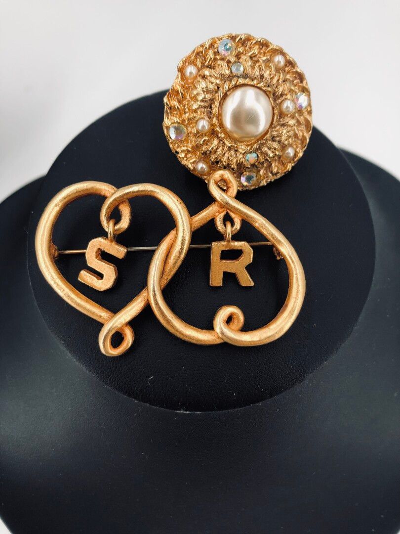 Null SONIA RYKIEL：镀金胸针，上面有两个缠绕的心和悬挂的SR标志。
附有一个镶有水钻和珍珠的圆形镀金金属胸针。