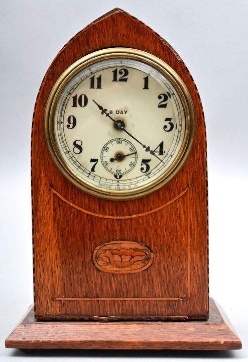 Tischuhr / Table clock 桌钟，美国，20世纪初。 表盘上有阿拉伯数字和偏心的秒针，椭圆形的木质表壳，装饰有一朵花和一个简单的带状镶嵌物，机&hellip;