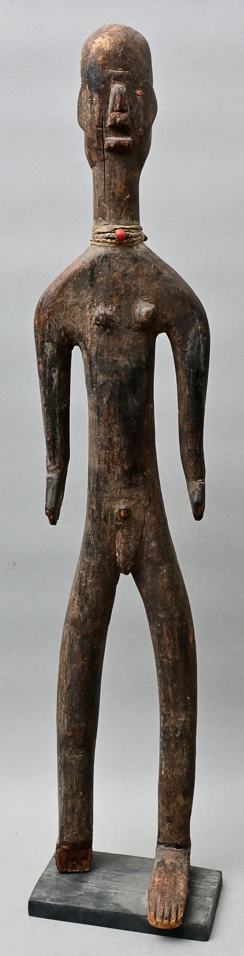 Null 图，坦桑尼亚，Nyamwezi (?) 具有女性和男性性特征的站立拟人图。浓重的风格化。木质，雕刻，有黑色铜锈。一只眼睛镶嵌在红色玻璃珠上，颈部有韧皮&hellip;
