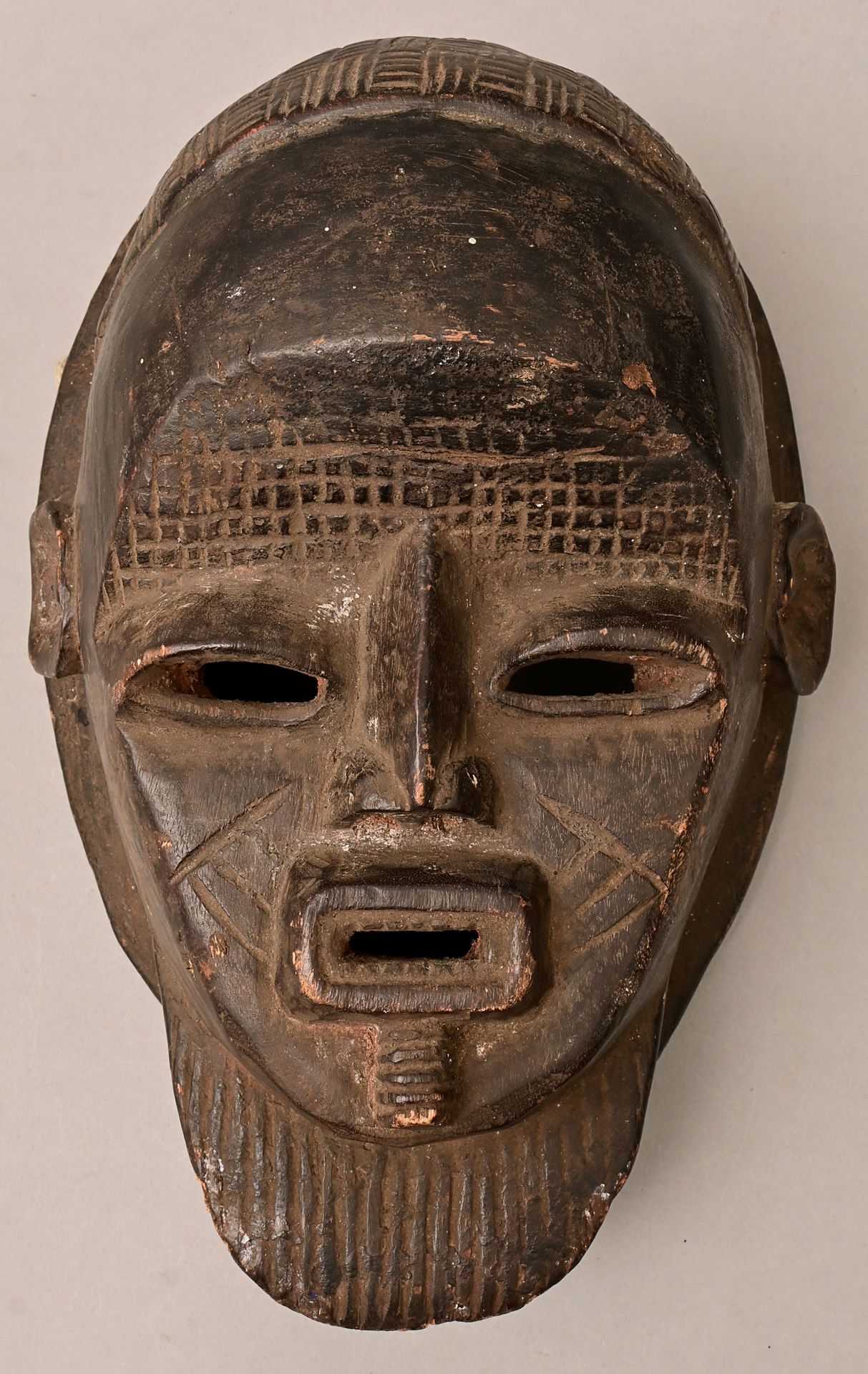 Null 面具，地区未定（可能是Igala/尼日利亚） 拟人化的脸部面具，木质，雕刻，有深色铜锈。凹槽模式。修复了轮辋处的孔。边缘处有旧的剥落。真实的岁月（和使&hellip;