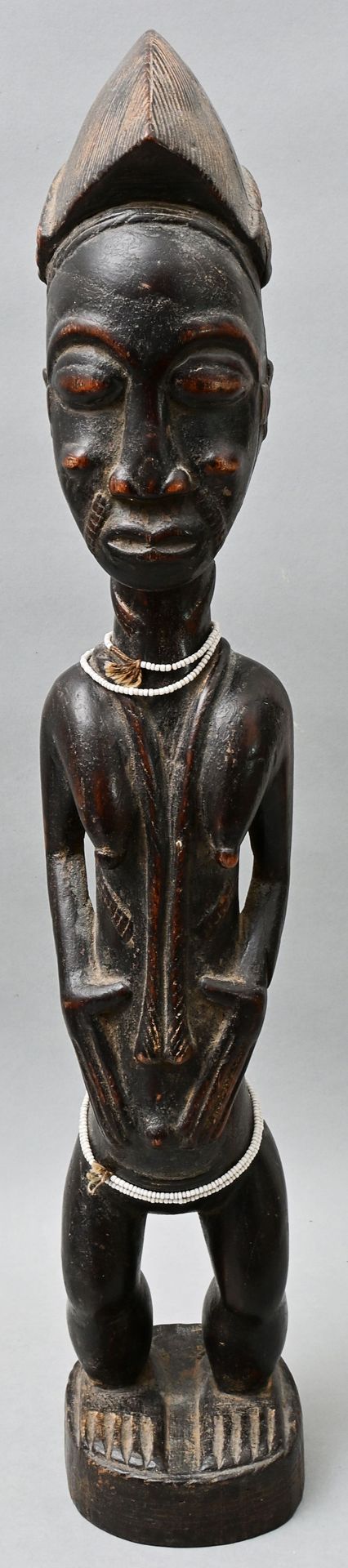 Null 雕像，象牙海岸，Baule 女性站立姿势的雕像。木质，雕刻，有黑色铜锈。一串串的玻璃珠子。脸上和身上有疤痕的纹身。高57厘米 出处：私人财产，符腾堡州&hellip;