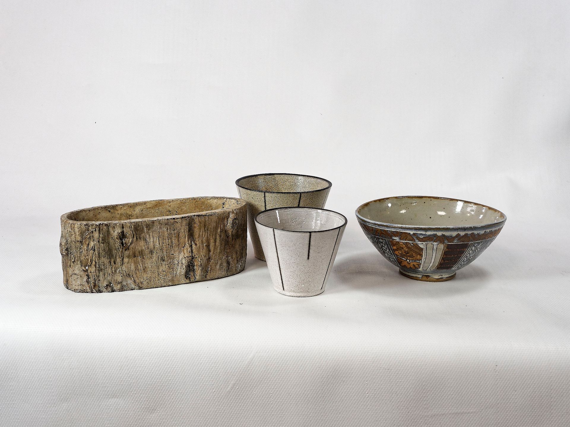 Null 拍品包括两个带有黑色条纹装饰的小陶瓷花盆，一个树干形的花盆和一个在底座下签名的大陶瓷碗，上面有保留的几何装饰。最大高度：10厘米。