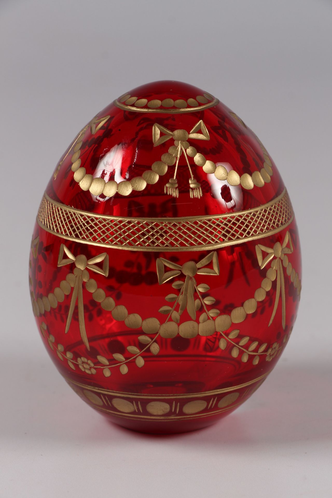 Null FABERGE.红色有色玻璃蛋，刻有花环的金色装饰。

在一个基座上，高10厘米。

最近的工作