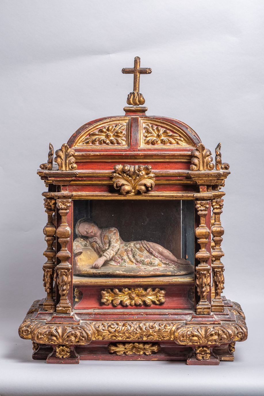 Null 55.一个18世纪的雕刻和镀金的木制灵位，里面有一个侧卧的雕刻和涂漆的木制圣人。(缺少一只手)。尺寸：45 x 15厘米。高度：60厘米。