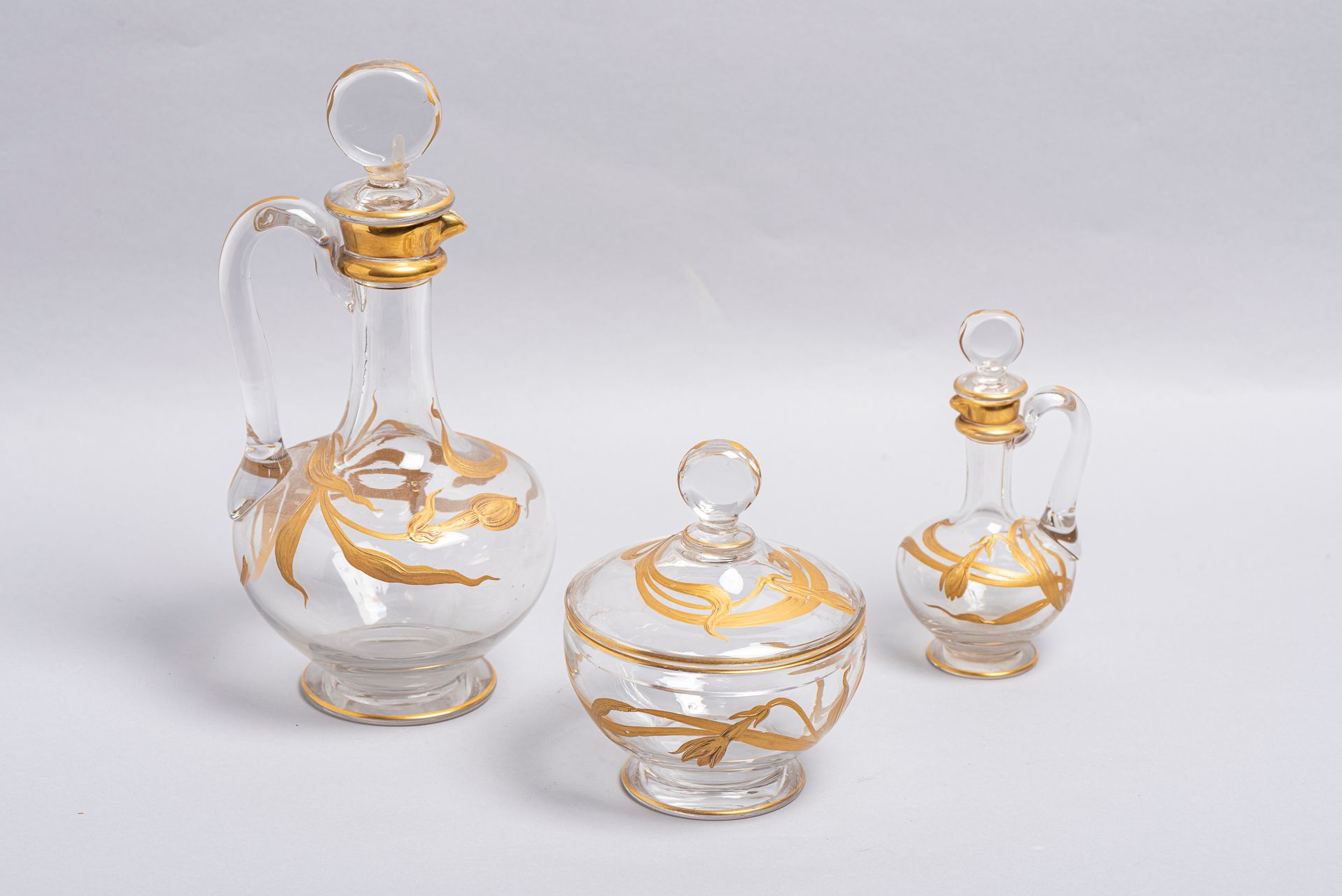 Null 
31.一套三件玻璃器皿，约1900年，包括一个咖啡杯，一个糖碗，一个有镀金植物装饰的瓶子（事故：瓶塞被粘回）。