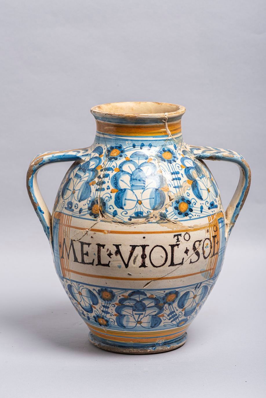 Null 33.一件16世纪末的Montelupo陶器药罐，双柄模型，上面有蓝色和赭石色的金刚砂装饰，铭文：MEL.VIOL.SOL在一个圆圈里。(断裂，粘在后&hellip;