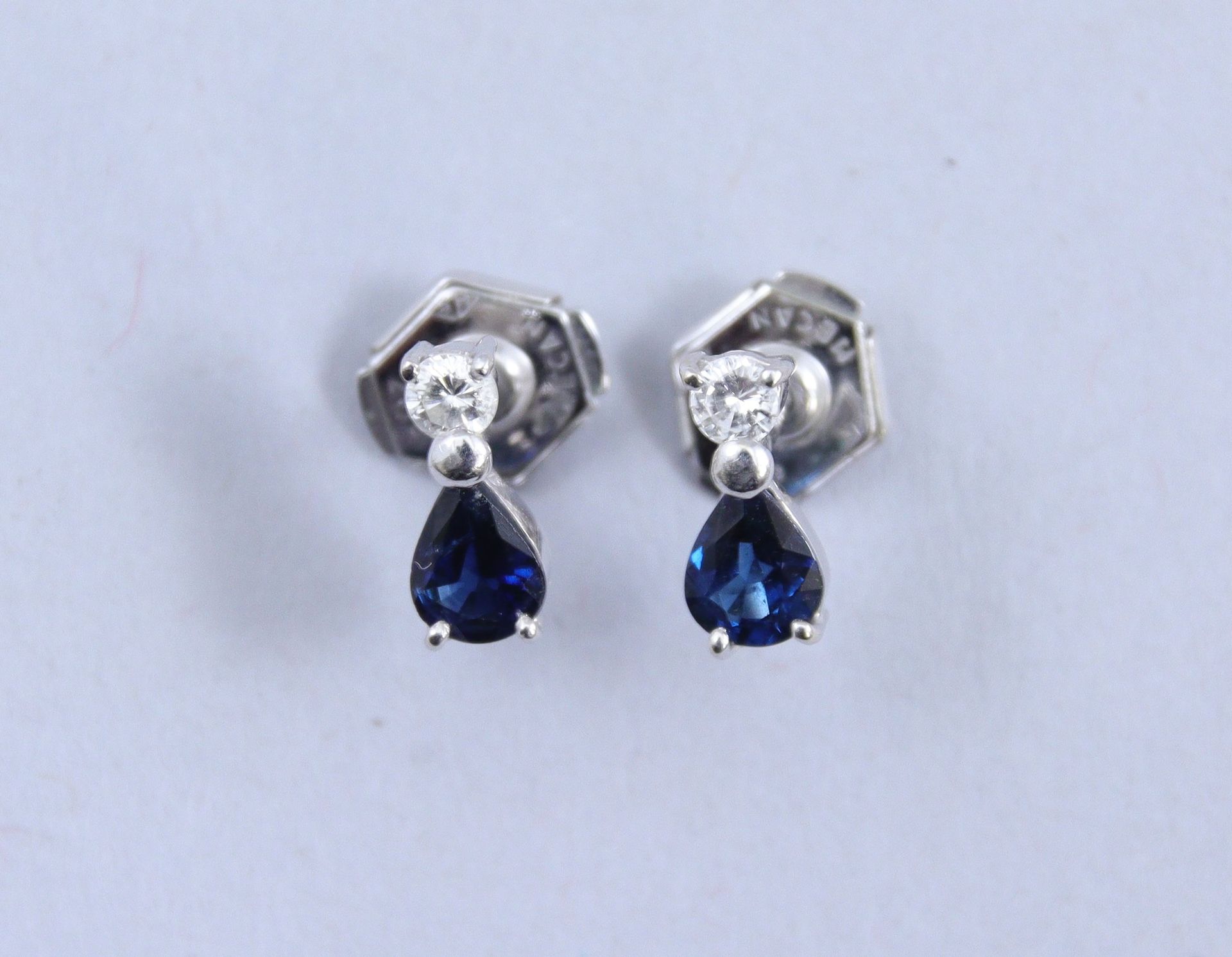 Null 一对吊坠耳环 

750千分之一的白金，装饰有一颗钻石，托着一颗梨形蓝宝石。

毛重：1,8克。