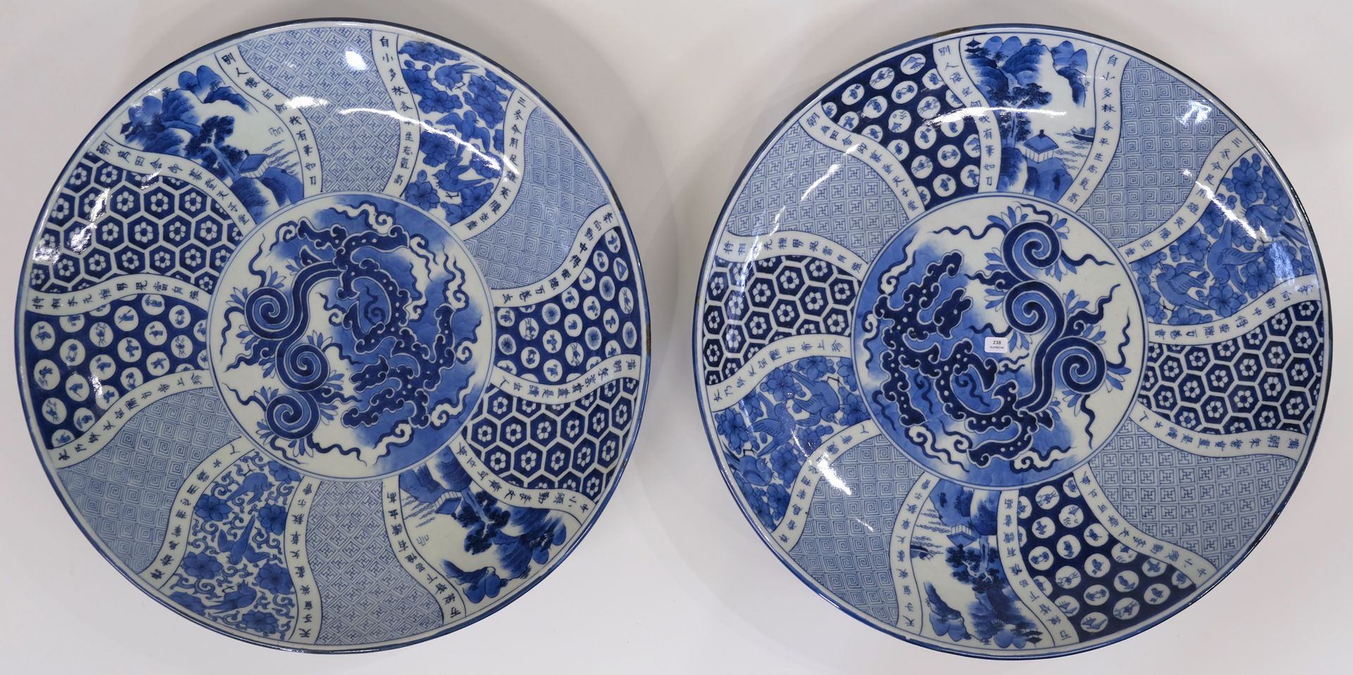 Null 一对大瓷盘，上有蓝色单色装饰，包括鸟类、风景和几何图案。背面有签名。日本，明治时期（1868-1912 年）。直径 48.5 厘米。