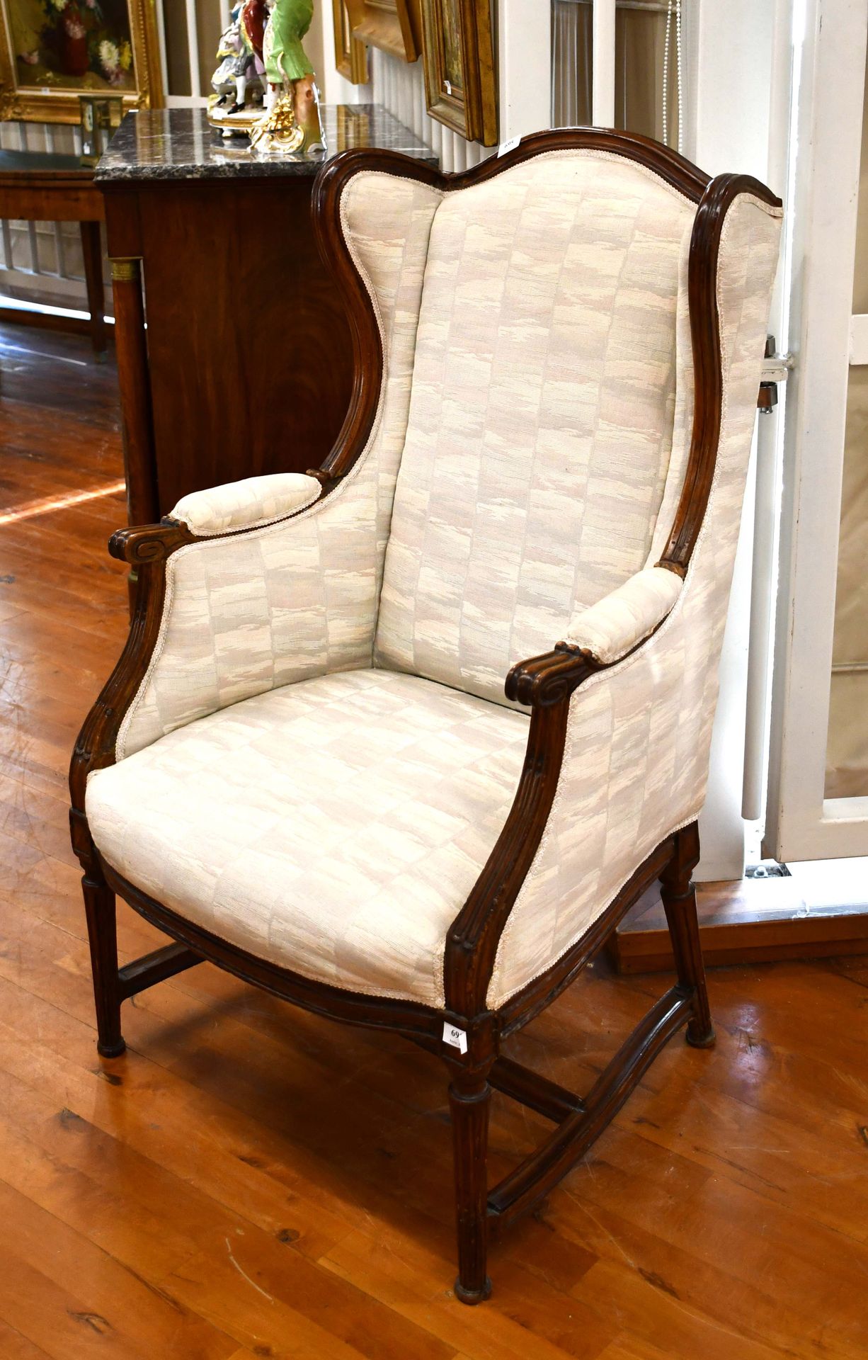 Null Louis XVI style wing chair with fluted legs connected by a brace
