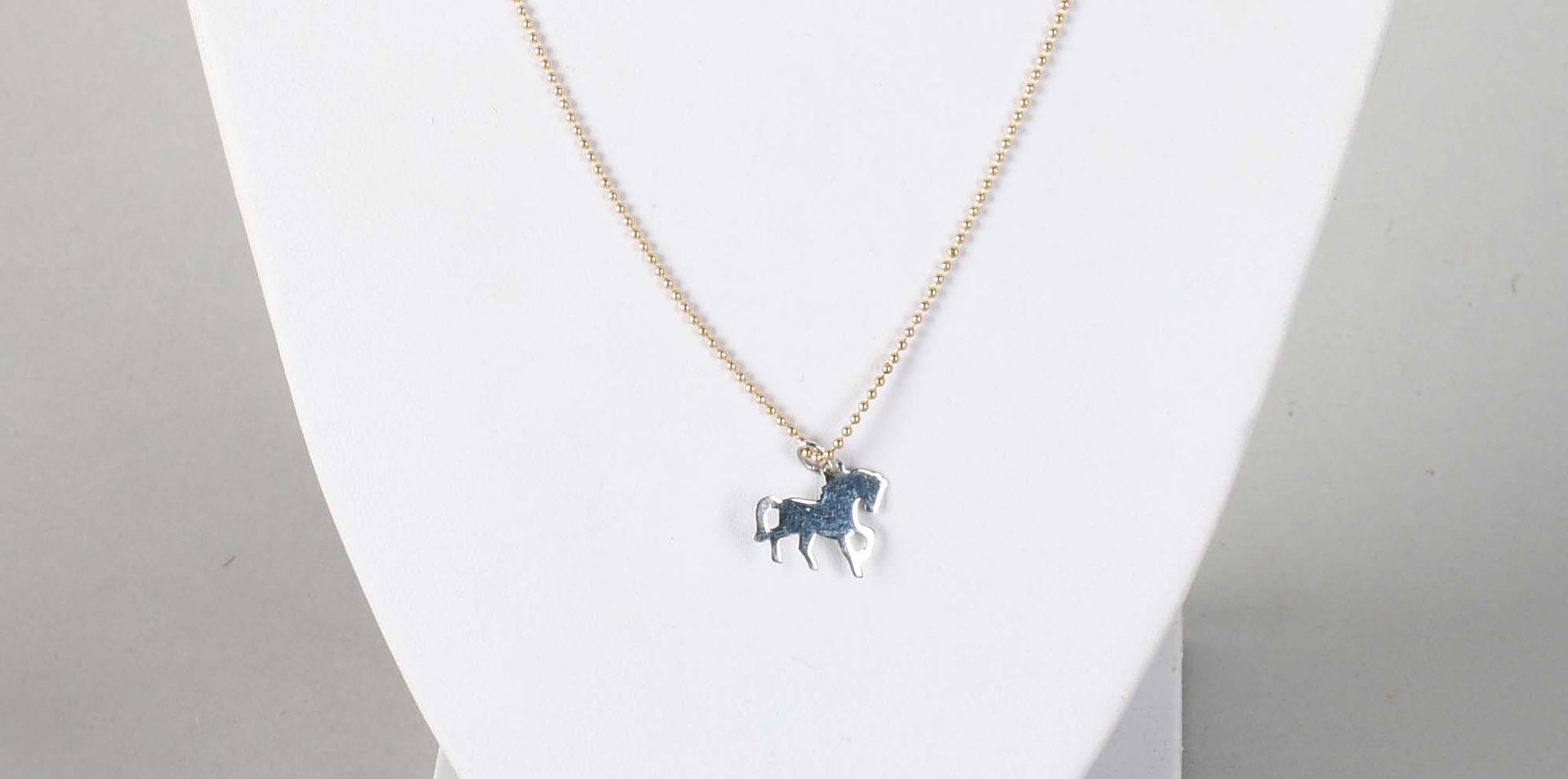 Null 珠宝首饰

一匹马形状的吊坠，18K白金，18K黄金的珍珠链。总重量：+3,9克。