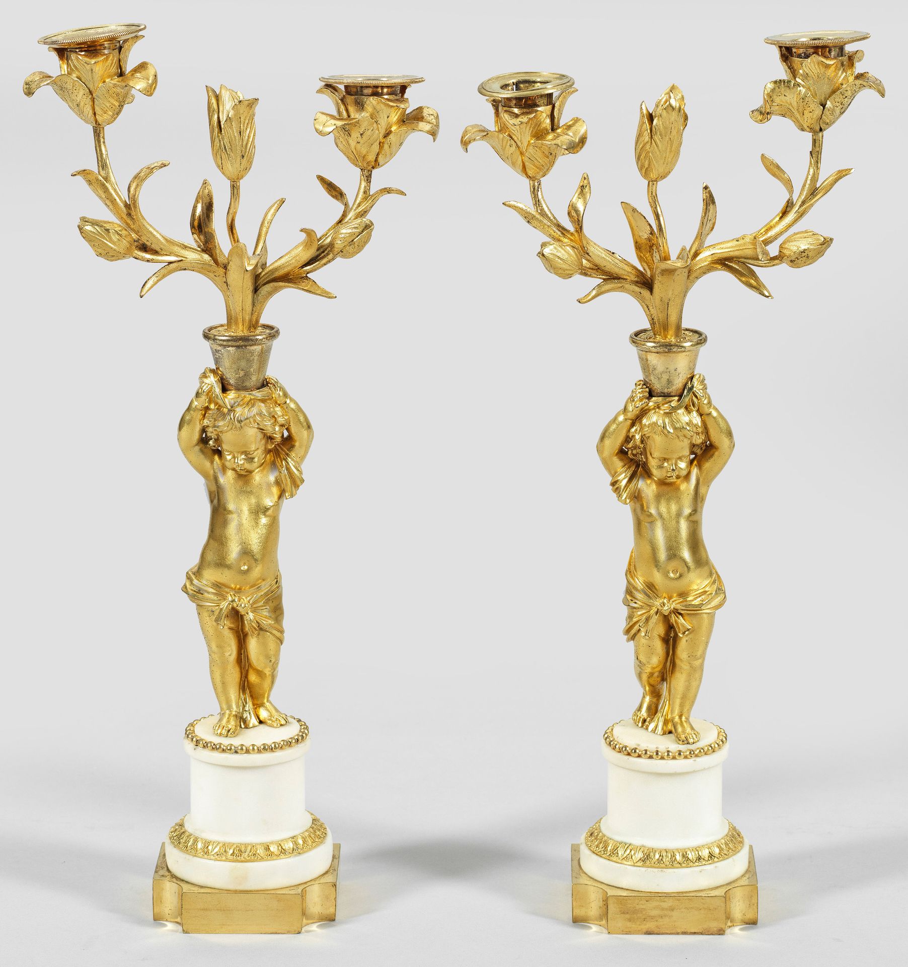 Null 一对路易十六时期的双灯对联。双灯；青铜、鎏金和白色大理石。短柱轴上有精细浮雕的棕榈楣和珍珠饰，柱轴上方是凹角的平基座。上方是一个雕刻完整的普托，作为花&hellip;