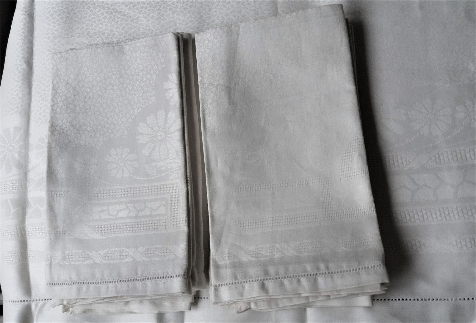 Null 桌布和12张餐巾，20世纪上半叶。
亚麻大马士革的桌布和12张餐巾，边框是双绳的大楣，上面有交叉的丝带和盛开的雏菊，桌巾也是同样的图案，大马士革的小鳞&hellip;