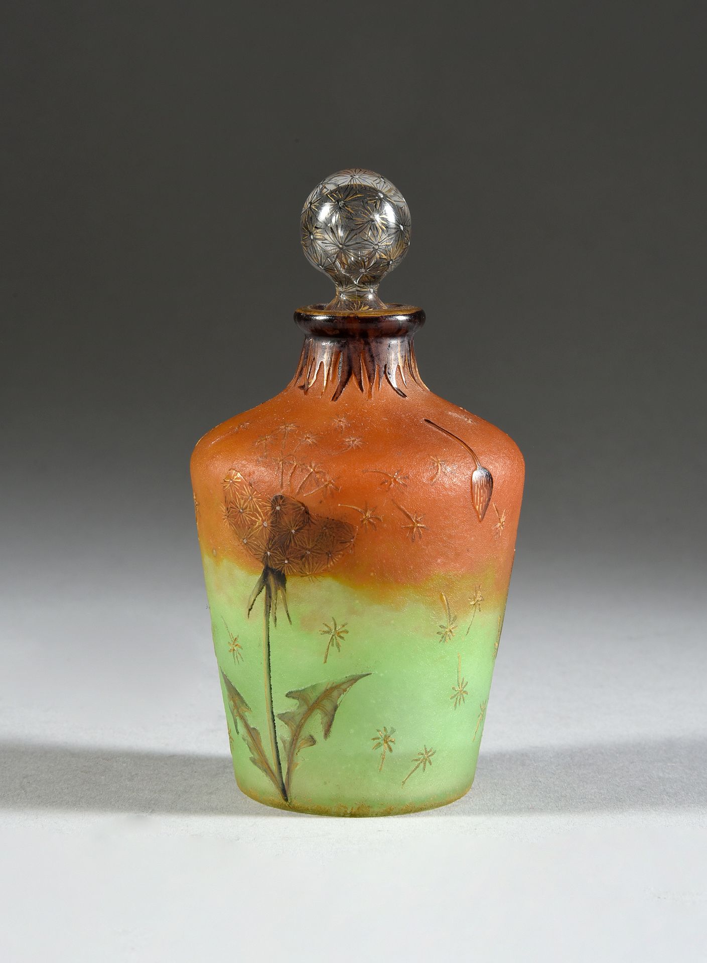 DAUM à Nancy 
蒲公英装饰的瓶子。
橙色和绿色背景的酸蚀和珐琅彩多色装饰的玻璃瓶。
蒲公英彩绘装饰的瓶塞。
高：11厘米。