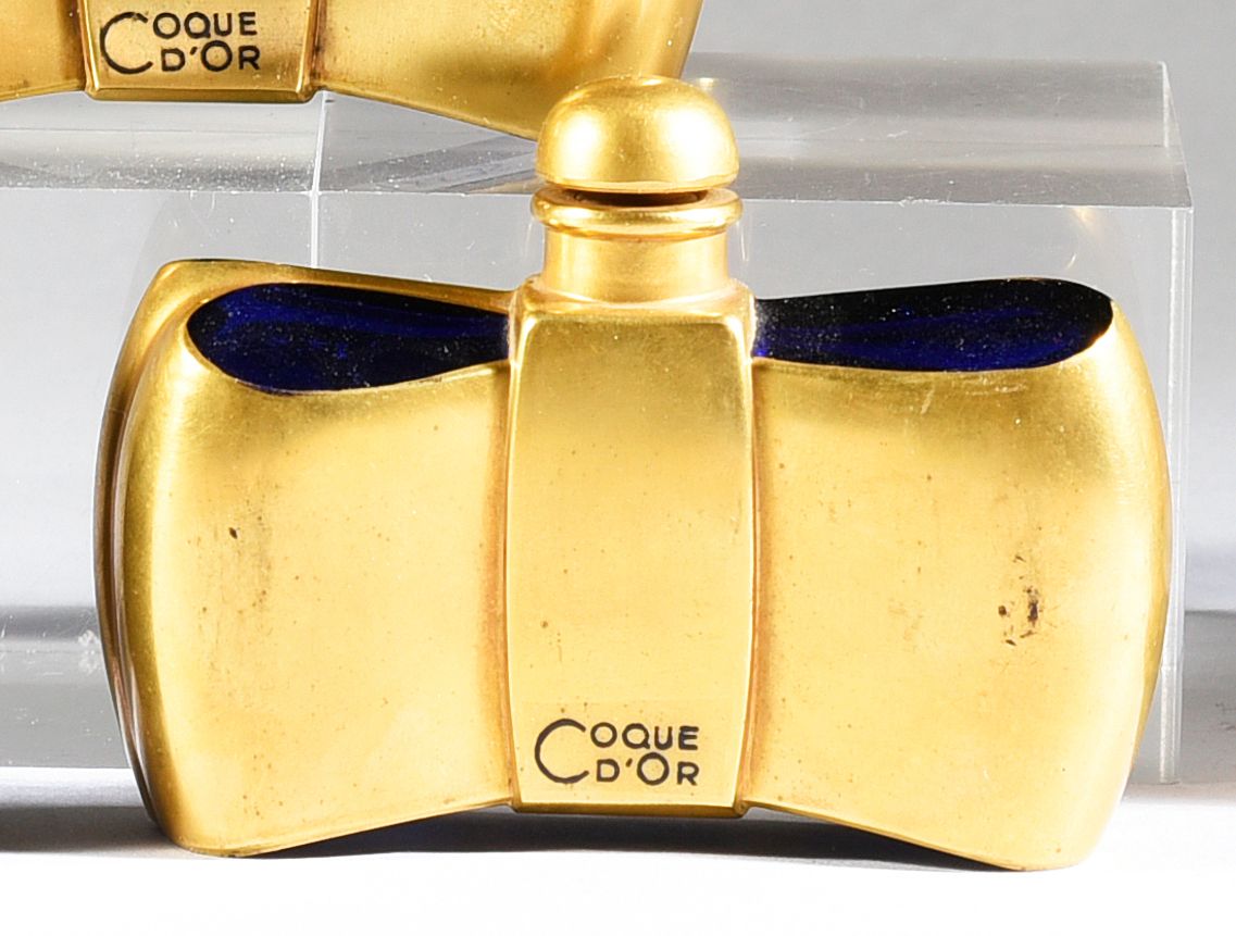 GUERLAIN - «Coque d'Or» - (1937) 
模制的午夜蓝色有色玻璃瓶，有一个带有丰富金箔的风格化蝴蝶结，顶部有一个配套的凸圆形瓶塞。两面&hellip;