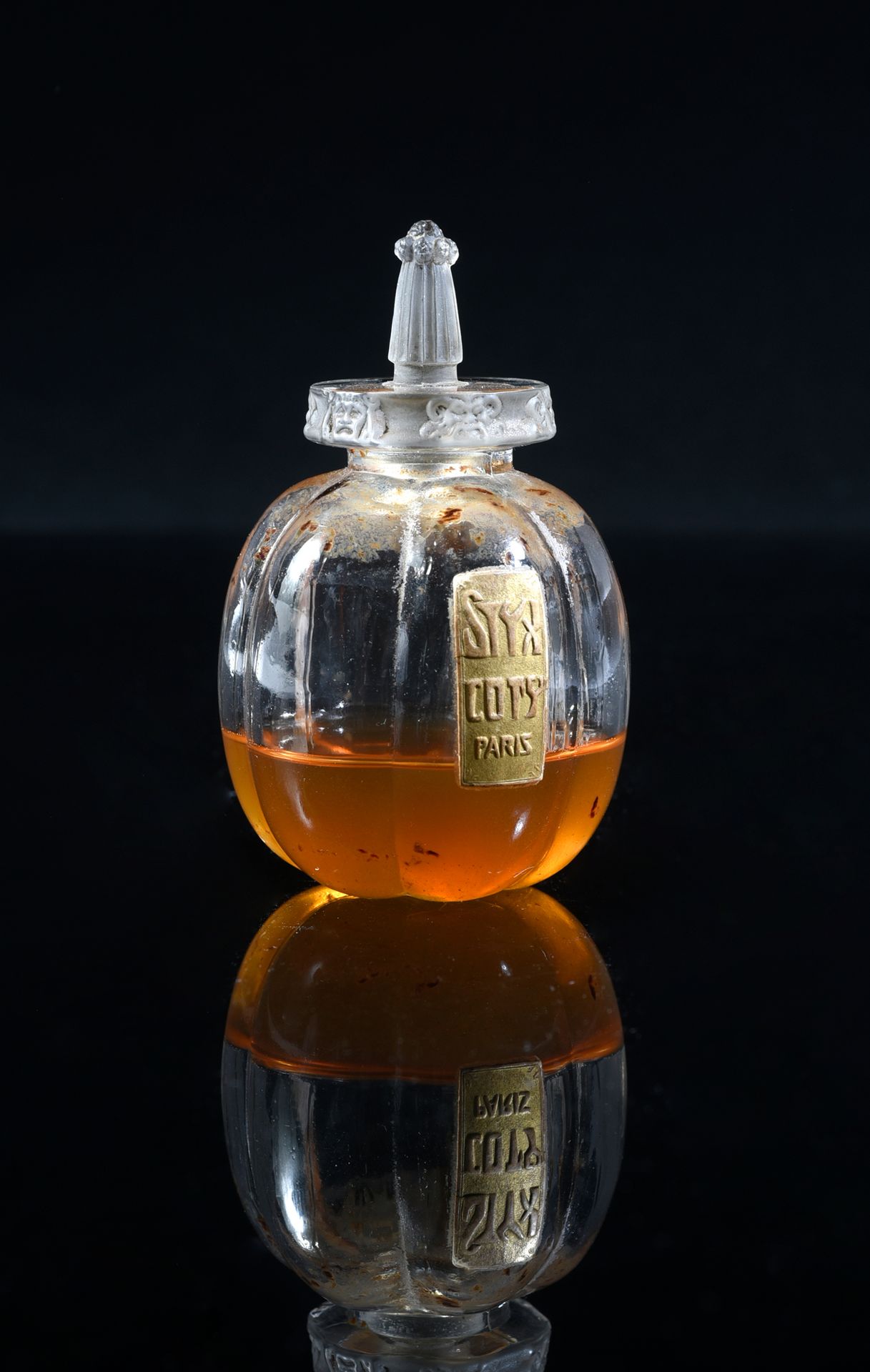 Coty - «Le Styx» - (années 1910) 
极为罕见的无色压制玻璃 "六个面具 "瓶，横截面为圆柱形，瓶身为六叶形，饰有浮雕金质标签，瓶&hellip;