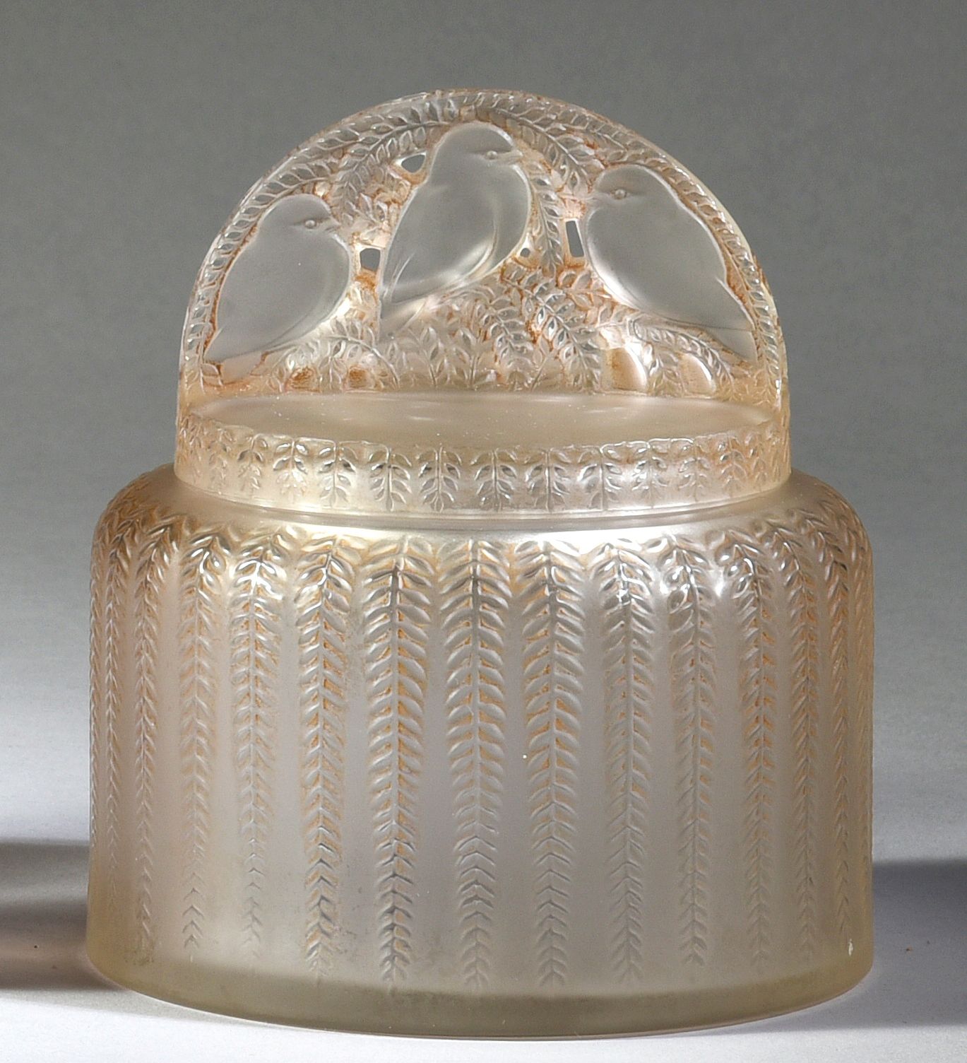 René Lalique & Cie - «Bombay» - (1933) 
无色玻璃压制的圆柱形鼓形香粉盒，上面装饰有树叶花环，盒盖上装饰有三只麻雀的叶子背&hellip;