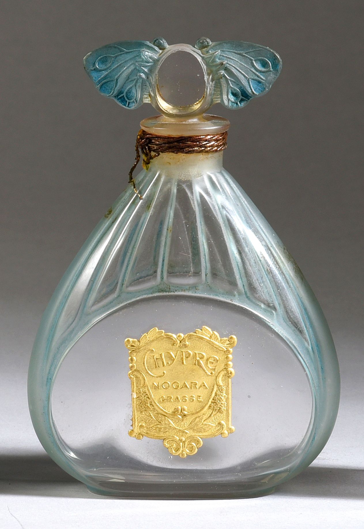 Nogara (Pelissier Aragon) - «Chypre» - (1920) 
无色压制的椭圆形玻璃瓶，三角形的弧形瓶身有蓝色斑驳的凹槽装饰，瓶颈&hellip;