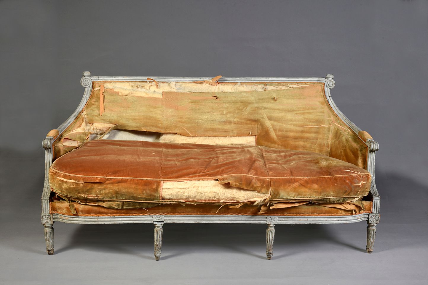 Null 土耳其风格的沙发，采用模压、雕刻和灰色漆面的木料，它靠在六条有凹槽和丝状的腿上，扶手上装饰着刺桐树叶，贡多拉形的背部有卷轴。
路易十六时期。
高：92&hellip;