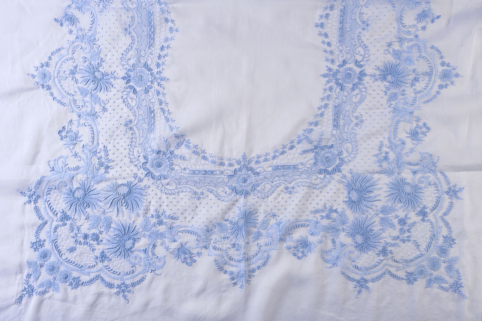 Null 蓝色刺绣欧根迪桌布，20世纪上半叶。
蓝色精细刺绣欧根迪的桌布，桌子中央极好的刺绣了菊花，叶子和花朵的花环的装饰，一些图案用非常细的线刺绣，点缀，边框&hellip;