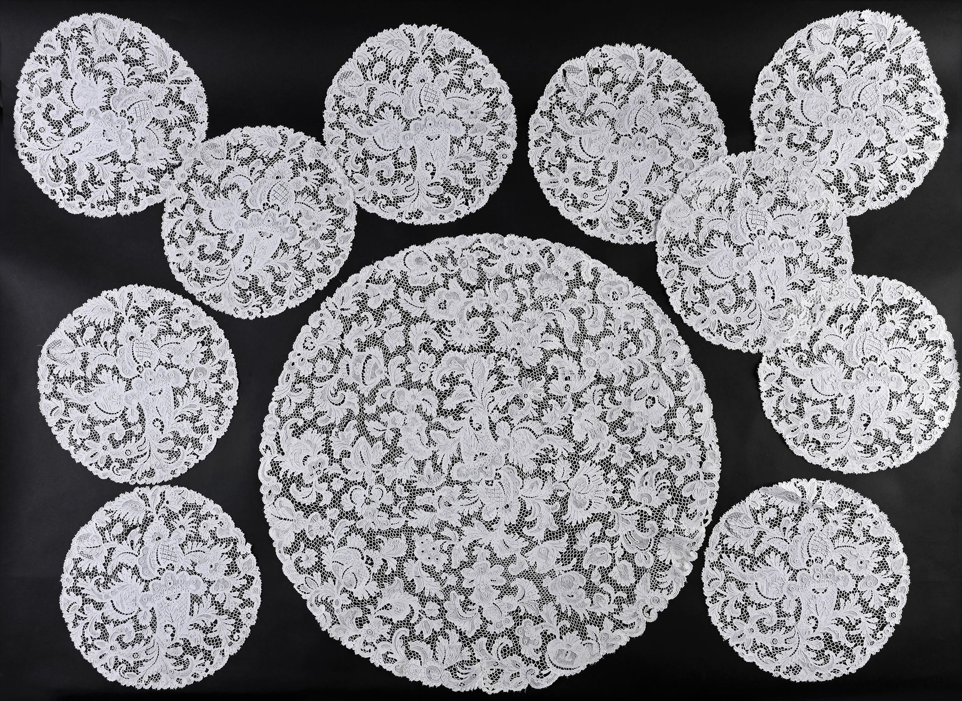 Null 中心装饰和10个斗笠，针刺，20世纪初。
圆形，有密集的花和水果的装饰，采用精细的针刺威尼斯花边。中心器皿的直径：65厘米，斗笠：每个29厘米（状况良&hellip;