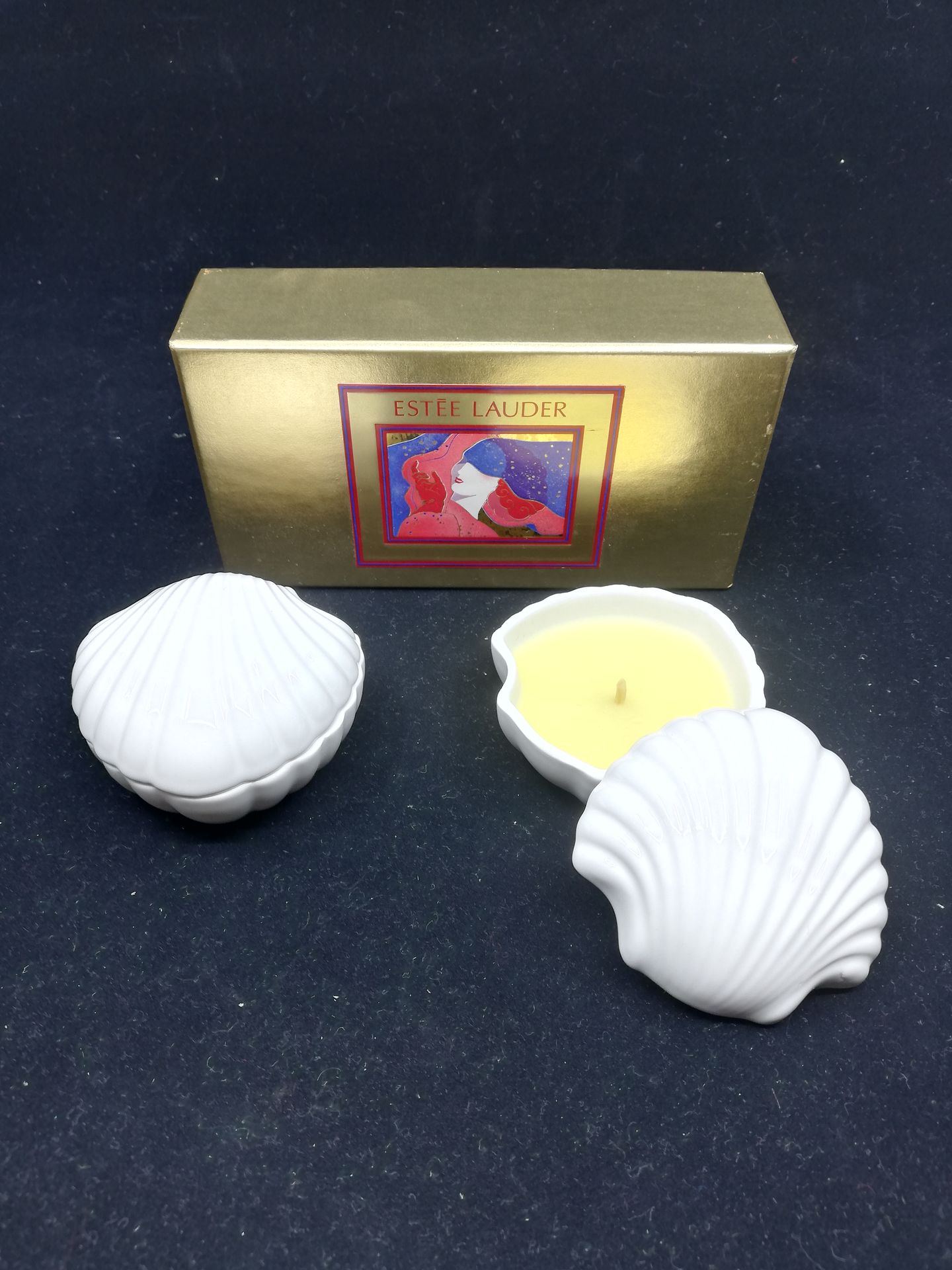 Null 雅诗兰黛 - (2000年代)

一个用金纸覆盖的纸板派对盒，上面有一个女人肖像的多色插图，里面有两根香薰蜡烛，用带贝壳的瓷器盒子装着。